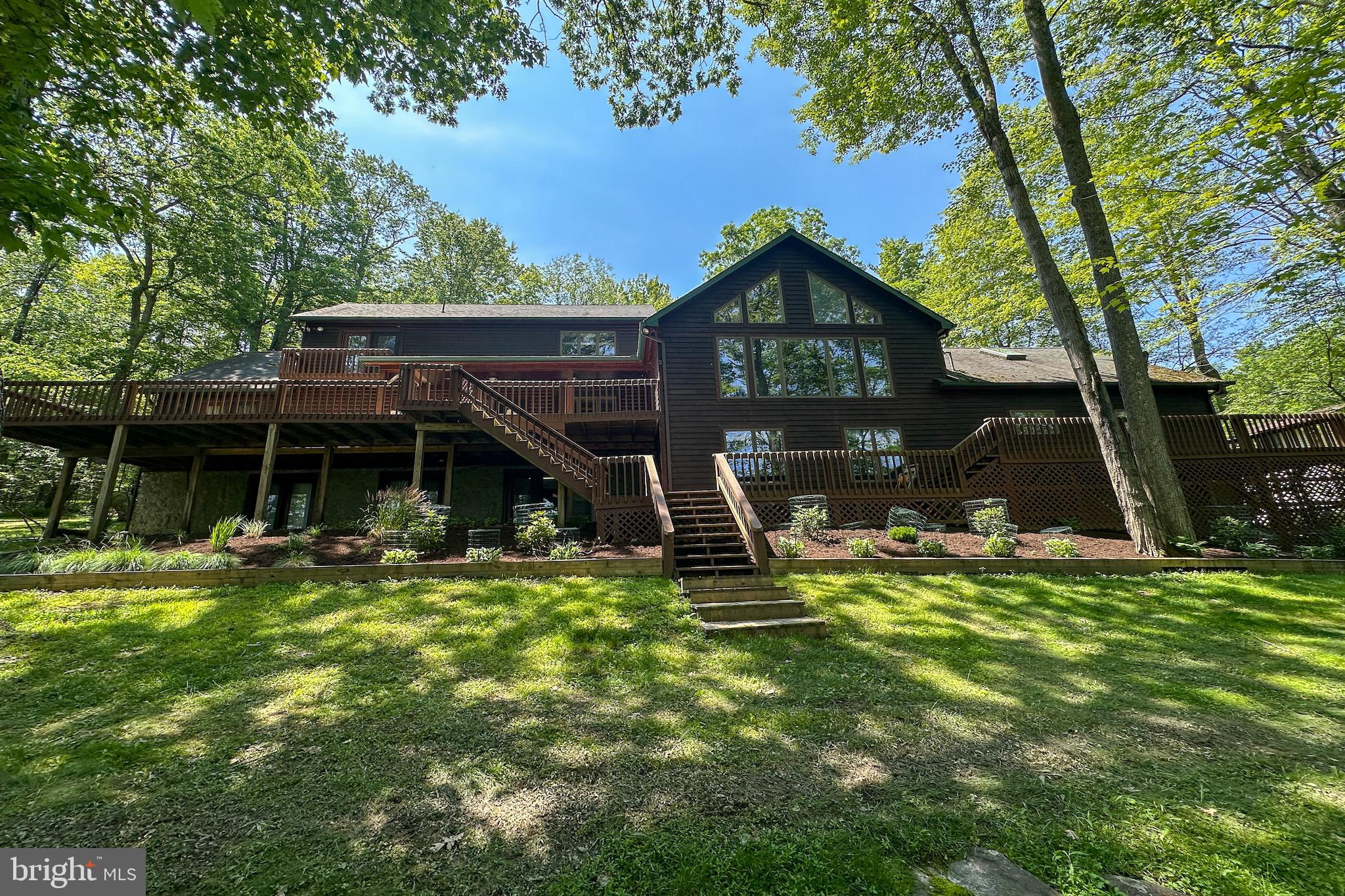 Exquisite Lakefront Log Home Retreat at Deep Creek Lake.
Nestled on a private, wooded 1-acre lot with 169 feet of pristine lakefront along a serene cove on the southern end of Deep Creek Lake, this well-maintained log home offers the perfect balance of rustic charm and luxurious lakefront living.
From the moment you arrive, the home’s park-like setting and lush landscaping welcome you into a world of tranquility. Step onto the expansive lakeside deck—partially covered for year-round enjoyment—and take in sweeping views of the water, the perfect backdrop for entertaining or peaceful morning coffee.
Inside, this spacious 4,284 sq. ft. retreat spans three levels and features 4 bedrooms and 3.5 fully updated baths. The main level primary suite boasts lake views, a walk-in closet, private bath, and direct access to the deck, offering comfort and privacy. Two of the upper-level bedrooms share a beautifully updated bath, both enjoying stunning lake views.
The heart of the home includes a grand lakeside great room with panoramic views, and an adjacent billiards room, both with forced-air heat and central A/C—plus a warm and inviting living room with an elegantly finished stone fireplace illuminated by spotlights. The open-concept kitchen features updated appliances, tile countertops, and a counter-height peninsula flowing seamlessly into the dining area, which also walks out to the lakeside deck.
The finished walk-out lower level is designed for relaxation and recreation with a family room featuring a wood stove set in a custom stone wall, plus a spacious rec room—all with access to a lakeside patio. A shared three-quarter bath on this level ensures comfort for guests.
Boating enthusiasts will appreciate the Type A dock permit, allowing two power boats—ideal for enjoying Deep Creek Lake to the fullest. A two-car attached garage and additional one-car integral garage provide ample storage, with extra driveway space for guests.
Whether it’s the intimate indoor details or the unmatched outdoor setting, this one-of-a-kind lakefront home delivers the ultimate Deep Creek Lake experience. Don’t miss this rare opportunity to own a luxurious escape in one of the region’s most peaceful coves.
Schedule your private showing today and experience lake living at its finest.