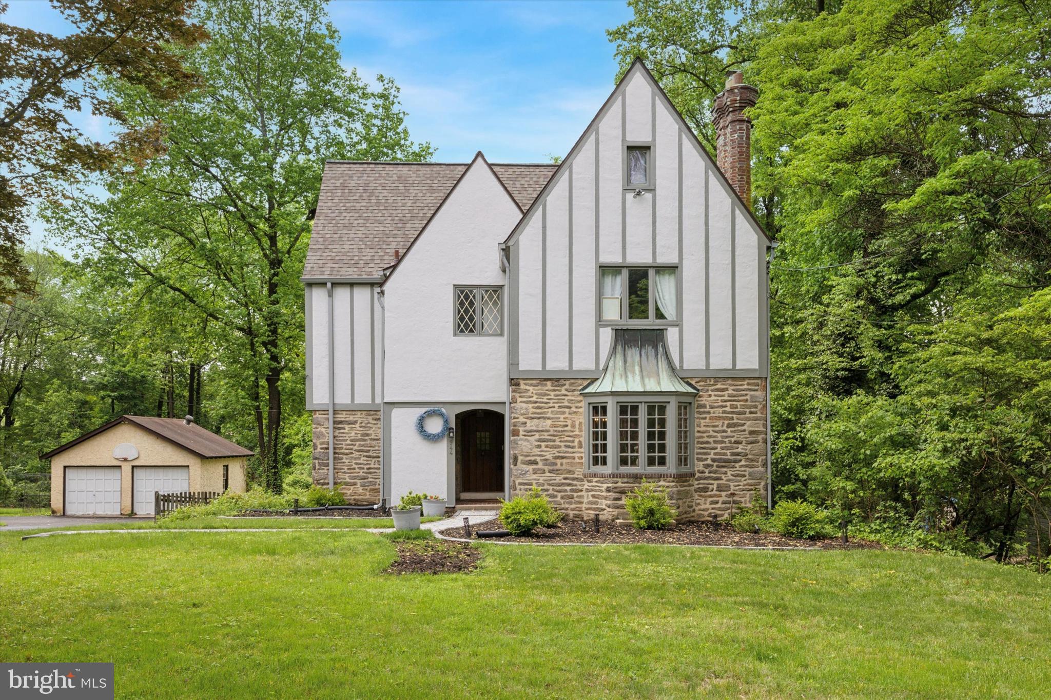 Step into timeless elegance with this beautifully renovated 5-bedroom, 3.5-bath Tudor nestled on a lush .64-acre lot in the sought-after neighborhood of Rydal, Abington Township. From the moment you arrive, the arched stone entry and original wood door set the tone for a home that blends classic charm with today’s modern comforts. Inside, you’re greeted by a sun-drenched living room anchored by a stunning stone fireplace with wood-burning insert. Imagine cozy evenings curled up by the fire, surrounded by built-ins, bay window views, crown molding and hardwood floors. The formal dining room, bathed in natural light, is perfect for hosting everything from holiday feasts to intimate dinners. Off the dining room, an inviting den beckons with vaulted ceilings, skylights, a dramatic stone accent wall and sweeping views of your private backyard retreat. The chef’s kitchen is a dream—outfitted with white shaker cabinets, sleek black granite countertops, stainless steel appliances, a pantry and subway tile backsplash—all anchored by elegant slate flooring. From here, step out to your expansive, maintenance-free deck and enjoy your fully fenced yard. Upstairs, the primary suite is a dream with a walk-in custom closet, gleaming wood floors and a marble en-suite. Two additional spacious bedrooms share a charming Jack-and-Jill ceramic tile bath, flanked by a charming built-in vintage linen closet for added character. The third floor offers two more sunny bedrooms with vaulted ceilings and a third full bath—perfect for guests, teens, or a private office. The clean, unfinished basement provides ample storage, laundry area and direct access to the yard. Bonus features include a convenient main floor powder room, new roof (2021), new hot water heater (2022), radon remediation system and an attached one-car garage. All of this, located in the award-winning Abington School District, just minutes from major highways, the train, shopping, dining, parks and more. A rare blend of old-world craftsmanship and modern living—this Tudor treasure is ready to welcome you home.