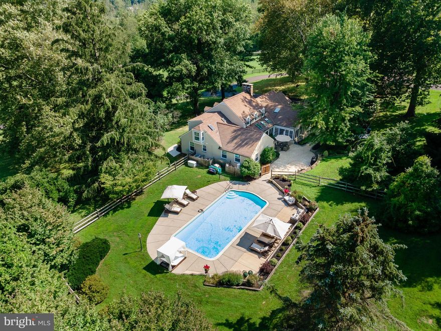 This bucolic property sits in the heart of desirable Chester Springs. As you approach the house by a long, tree-lined winding drive you will appreciate the privacy and amenities this beautiful home has to offer. Sitting on over 7 acres in a quintessential country location, this fully updated farmhouse with five stall barn, riding ring, paddock, and swimming pool offers an oasis from today’s busy lifestyle. Enter the house into a gracious through center hall with views of the beautifully landscaped rear terrace. To your right is a large formal living room with fireplace and custom millwork. The formal dining room with wainscoting provides opportunity for more structured entertaining. These rooms are adjacent to a spectacular kitchen and family room, highlighted by cathedral ceiling and iron trusses. This comfortable and stylish space provides the open concept that is so popular with today’s buyers. The kitchen is a chef’s delight with stainless steel Thermador appliances, including a six-burner gas range. There is generous counter space and an island with breakfast bar. The family room boasts a floor-to-ceiling stone fireplace and wall of windows which infuse the space with natural light. A large main floor laundry room with plenty of storage is just off of the kitchen. There is a cozy den adjacent with built-ins, a family entrance with a very large mudroom with stone floor and a convenient powder room. A useful library with more built-ins and bar area is also found on this level, providing even more space for work from home or relaxing. Finally, a much sought-after main floor master bedroom with ensuite newly remodeled bath and private hallway finish the first floor of the house. The second floor features three newly carpeted, generously proportioned bedrooms and a hall bath. The outdoor features of this property are spectacular. A large pool perfect for swimming laps and multiple patios with plenty of space for entertaining or relaxing with friends and family surround the exterior of the house. A dedicated powder room has outside access. These spaces feature beautiful landscaping and views of the surrounding countryside and imbue the property with a calm serenity. Perfect for horse and animal lovers is the newly rebuilt and refurbished barn with seven stalls, tack room, washroom, its own front porch, and two outdoor stalls. The barn has loft space ideal for storing hay. Two paddocks and a riding ring provide amenities for the horse enthusiast that make keeping your own animals easy. There is also a chicken coop, and two more utility sheds on the grounds. This is all surrounded by the horse trails that Chester Springs is known for. Very conveniently located in close proximity to the PA Turnpike, shops, dining, and award-winning schools. This is truly a special home on a fine piece of property, perfect for creating your own peaceful retreat. Showings begin on 9/7.