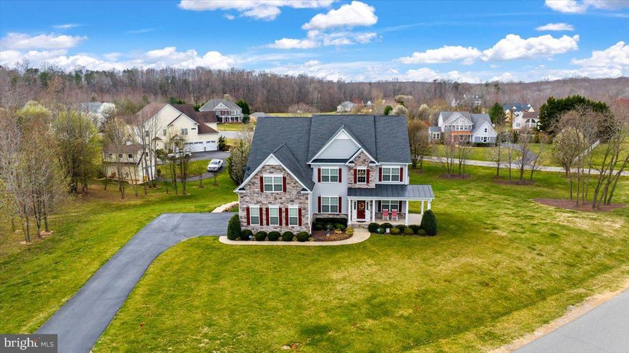 A refined estate of timeless elegance, poised on 2.44 pristine acres in the coveted, no-HOA enclave of Bloomsbury Farm Estates... just minutes from Fredericksburg’s finest conveniences! Welcome to 6706 Pond View Lane – an exquisite residence that seamlessly blends classic sophistication with modern comforts, offering over 5,600 finished square feet of impeccably designed living space. Built in 2015 by Atlantic Builders and masterfully maintained, this distinguished Whitman II floorplan is appointed with thoughtful upgrades and meticulous detail throughout. From the moment you arrive, its slate gray façade, accented with stonework and brick-toned shutters and door, exudes stately charm. A curved asphalt driveway, framed by flowering trees, leads to a side-loading three-car garage, offering both function and elegance.  Step onto the gracious wraparound front porch, where serene sunset views await – enhanced by the warmth of conveyed rocking chairs, inviting you to unwind in style. The grounds are an artful blend of manicured landscaping, vibrant flora, and tranquil green spaces, culminating in a backyard retreat featuring an expansive Trex deck, a custom patio with built-in seating, firepit, and a well-appointed shed for discreet storage. Inside, the grandeur continues. A soaring two-story foyer welcomes you with gleaming engineered hardwood floors that flow effortlessly through the main level. Designed for effortless entertaining and everyday living, highlights include a formal living room with porch access, an elegant dining room, a richly appointed office, and a spacious laundry room with abundant storage. The two-story family room dazzles with floor-to-ceiling windows and a commanding stone fireplace, creating a luminous and inviting gathering space. The gourmet kitchen is a chef’s dream, anchored by a central island, upper level granite countertops, rich espresso cabinetry, and GE Profile appliances including a double oven. An adjacent butler’s pantry ensures seamless entertaining, while the sunroom just beyond provides an idyllic setting for casual meals and opens directly to the outdoor deck. Upstairs, four luxurious bedrooms and three full baths await. The palatial primary suite includes a vast sitting area, dual walk-in closets, and a hallway of mirrors – a private, boutique-like dressing experience. The spa-inspired ensuite bath features granite-topped dual vanities, a garden tub, and an expansive, tile-surrounded shower with seating. The additional bedrooms are generously proportioned, with walk-in closets and private or semi-private bath access. The fully finished lower level is an entertainer’s haven, adorned with luxury vinyl plank flooring and versatile spaces including a media room, home gym, and a sprawling recreation area with a granite-topped bar. An additional bedroom with walk-in closet, full bath with custom tile shower, and an oversized unfinished storage room enhance the functionality. French doors provide seamless access to the backyard oasis. Ideally situated, 6706 Pond View Lane offers the serenity of country living with unparalleled proximity to modern amenities – grocery stores, shopping, dining, and healthcare are just minutes away. Major thoroughfares including I-95, the Spotsylvania VRE station, and Downtown Fredericksburg are all within 15-20 minutes. For the discerning buyer seeking elegance, space, and privacy without compromise – this estate is a rare offering!