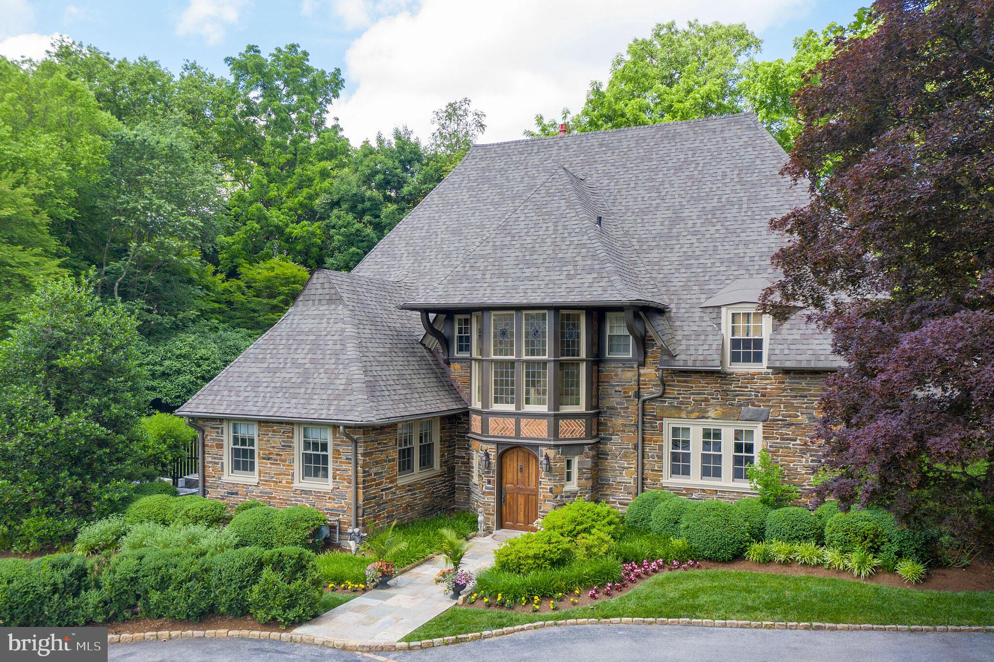 If you are someone who has an appreciation for old-world charm with stunning upgrades and fixtures and an abundance of space for family and friends, then this 1920 s English Tutor home can t be missed. Through the gated driveway with stone pillars is a charming cobblestone courtyard with parking for at least 6 cars. The driveway continues around the side of the house to a 2 car garage with rear entry and even more open space for parking or a game of half-court basketball. The interior of this home has been meticulously updated and maintained, including a large 2-story addition in the rear that accommodates a modern open kitchen and family room on the first floor and an incredible master suite on the second floor. As you enter through the original hardwood door into the foyer, you are immediately greeted with the warmth of a home that begs to entertain. A formal living room to your left with gas fireplace and entry into a salon room, filled with natural light and perfect for a games room or office. Lovely glass door in the living room leading to gardens. To the right of the entry is the formal dining room with incredible floor to ceiling windows and picture molding. Through the service pantry with laundry room, is the eat in kitchen and bumped out family room with tray ceiling and a projector system for family movie nights. Oversized French doors from the kitchen eating area lead out to the spectacular rear yard with flagstone patio. This area was meant for al fresco summer dinners, relaxing in the sun, and entertaining, with a yard that absolutely delights! Mud room off the service pantry hall leads to the garage and also to guest quarters above garage. Up the main stairway, you ll be delighted by the 4 original leaded glass windows. On the second floor is the sprawling master suite with 2 walk-in closets, cozy gas fireplace, and a massive bathroom with his and hers sinks, vanity, extra large glass shower, and jetted tub. Another en-suite bedroom, plus 2 more bedrooms and a full hall bath complete the second floor. Third floor has an abundance of flexible space, currently being used as 2 bedrooms and an office. A full hall bathroom and a walk-in closet are also up on the third floor. The full basement has an enormous unfinished section with an abundance of storage space, plus a finished section for more hang out space and a second kitchen area with extra fridge space, cabinetry, and sink. Home generator covers all essentials. This impressive home is walking distance to the train and Suburban Square. You'll love this Main Line gem!