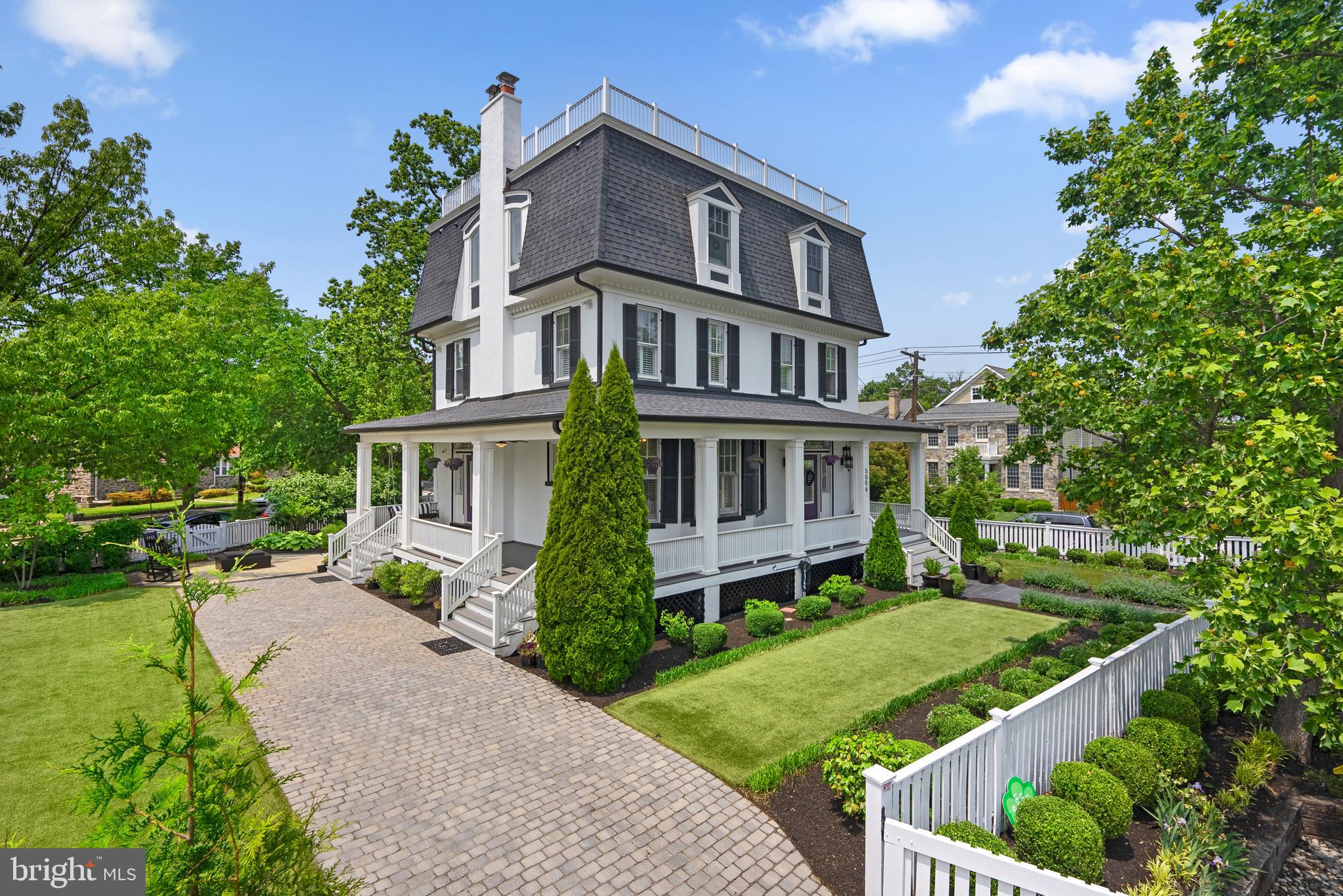 It is a rare occurrence to come across a truly one-of-a-kind property, one with rich history, beauty, and elegance. 5006 Piney Branch Road NW, in coveted 16th Street Heights, is all that and more. In close proximity to downtown Washington, D.C., this gorgeous property is nestled on a private island bordered by Gallatin Street and Iowa Avenue, adjacent to one of D.C.'s finest Charter Schools. The property enjoys romantic covered porches, specimen plantings, and masterful landscaping. Often called the "Gaga" house, the enchanting 1913 Victorian was designed and reimagined into a Second French Empire style home by a DMV native. The grand-scale residence is truly a classic to be cherished. The generously scaled entry, living and dining rooms feature two impressive fireplaces with mirrored glass surrounds, high coffered ceilings with black detailed trim and hardwood oak floors. Sun-filled, leaded glass windows open to reveal fabulous views of the grounds and expansive gardens. The dining room offers guests another view of the wood-burning fire-pit and synthetic lawn and mature plantings. The kitchen and breakfast/living room were added to the home during an extensive renovation by Centerline Design which also included raising the third attic level to a full floor and replacing the pitched roof with a mansard roof. The chef-inspired kitchen has all stainless steel appliances including a 6 burner cooktop, refrigerator/freezer, and a double oven with a custom hood imported from Mexico. The adjoining breakfast/living room is washed in sunlight from the oversized windows on three walls and has easy outdoor access and a juliet balcony.The second level offers 4 large bedrooms and 2 full bathrooms including a washer and dryer and the home’s original clawfoot tub. The western bedroom has a private covered porch with tree top views. The primary bedroom suite completes the third floor and includes a star-studded dressing room with a mirrored glass vanity and own washer and dryer, a spa-inspired luxury bathroom, a dramatic sitting room, a private office area, custom built-ins with museum lighting and hardwood floors. The sitting room and custom built-ins were just completed this year during the second renovation by Meridian Homes. The lower level has additional living space with a private recreation room, exercise and utility spaces with built-ins and washer and dryer. The guest suite with an entrance from inside the home and private exterior entrance includes a complete kitchen, large bedroom with washer and dryer, full bathroom and a sunken living room with built-in shelving and drawers. The residence has many unique features including designer lighting, extensive millwork and crown moulding throughout, custom-built -in shelving and pocket doors (single and double) plus four built in dog houses.
The landscape scheme offers evergreen and flowering bushes for full year enjoyment and was designed to maximize privacy. The paver driveway has room for three cars comfortably plus a tesla charger. There are several patio destination areas-one under the boughs of the willow tree on the tip of the Island and another framed by a handmade rose arbor that was built using the original shutters from the home that were removed during the expansion.