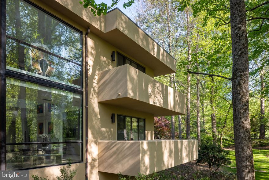 A two story gallery wrapped around an indoor koi pond forms the center of this quietly remarkable residence, where water, light, and movement shape the experience of the home from within.

Concealed within more than eight wooded acres, the approach unfolds gradually through dense trees before the architecture reveals itself, defined by strong horizontal lines, cantilevered forms, and a natural material palette that sits comfortably within the landscape.

Inside, the plan balances openness with clarity, offering a rare combination of architectural intent and everyday livability. Formal living and dining rooms, expansive gathering spaces, a dedicated office, and a well appointed kitchen with adjoining breakfast area are arranged with purpose and ease.

The upper level includes four generous en suite bedrooms, including a guest suite with a striking elevated terrace positioned within the treetops.

Constructed with steel framing and expansive structural glass, the home reflects a level of engineering integrity that supports its architectural ambition. Designed and built by local builder and engineer Jack Wilmore, whose background is rooted in generations of residential design and construction, the house carries a clear sense of authorship and discipline throughout.

Additional features include a three car garage, multiple outdoor terraces, and a setting that offers both privacy and proximity to the Washington metropolitan area.

A distinctive offering for those who value architecture that is considered, enduring, and deeply livable.

A detailed video is available by searching the property address.