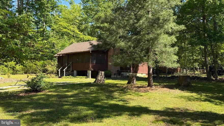 Nestled in the serene community of Shannondale, this charming cabin-style home offers a perfect blend of comfort and nature. With 1.36 acres of lush surroundings, enjoy breathtaking views of trees, woods and mature, flowering plants right from your doorstep. This inviting 3-bedroom, 2-bathroom residence features a cozy fireplace, ideal for creating warm memories during chilly evenings.   Enjoy the classic screened-in porch on those cooler, late summer evenings.  The spacious layout, with 1,442 sq ft of living space, includes a lower-level laundry area for added convenience. Built in 1967, this home exudes character with its classic frame construction and a mix of wood, vinyl, and carpet flooring. The peaceful ambiance is perfect for relaxation, while the ample outdoor space invites you to explore and unwind. With a driveway for easy parking, this property is a true retreat from the hustle and bustle. Embrace the tranquility and make this delightful home your own, where every day feels like a getaway.