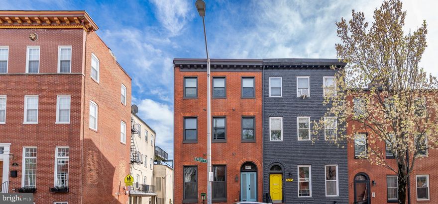 Thoughtfully reimagined by Baltimore designer Charlene Doverspike, 1917 E Pratt Street is a bold yet timeless city residence that blends original character with high-design modern living. Located on a sun-soaked corner in the heart of Butcher’s Hill, this 4-story brick end-unit townhome offers a rare combination of architectural charm, natural light, flexible space, and income potential.

Inside, clean lines and curated finishes invite you into a home built for both everyday ease and stylish entertaining. Wide-plank wood floors, oversized windows, and high ceilings set a rich tone across open living and dining spaces, while a contemporary kitchen with direct access to the rear patio makes al fresco dining effortless. The upper levels include multiple living zones, spacious bedrooms, and a serene primary suite retreat with its own floor, spa-inspired bath, and private city-facing balcony.

On the lower level, a fully outfitted one-bedroom apartment with separate entry and laundry provides the perfect guest suite, rental unit, or extended family space—offering privacy and versatility rarely found in downtown city living.

Step out the front door and you’re just blocks from Patterson Park, Charmed Café, Marta, Peter’s Inn, and some of Baltimore’s most beloved spots. Whether you’re unwinding with a book from Greedy Reads or grabbing a scoop from BMore Licks, the Butcher’s Hill lifestyle delivers walkability and charm at every corner.

A home that makes a statement—designed for those who appreciate both elegance and functionality in one of Baltimore’s most vibrant and established communities.

Highlights:
4 Bedrooms / 4.5 Bathrooms
 2,466 total square feet across 4 levels
Designer renovation by Charlene Doverspike
Separate 1-bedroom apartment on lower level
Exposed brick, original hardwoods & custom finishes throughout
Chef’s kitchen with rear patio access
Top-floor primary suite with private balcony
Prime corner lot in the heart of Butcher’s Hill
Close to Hopkins, Fells Point, Patterson Park, and top local businesses