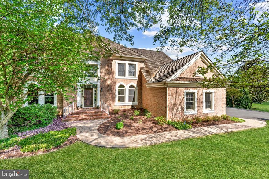 Sited on a tranquil, wooded lot within an idyllic cul-de-sac of just fifteen homes, 10728 Hunters Place is the quintessential stately colonial home built by the acclaimed Stanley Martin Homes. The Milburne model, an award-winning floor plan, boasts over 4,700 square feet of ethereal living space over two levels, with an above grade walk-out lower-level offering an additional 2400 square feet. Four sides of brick, intricate trim, and a side-load three car garage are distinguishing features of the exterior, signaling the premium construction and meticulous updates which have gone into the home. Inside, one is greeted by a soaring double-height foyer, whose sweeping curved staircase and marble floors are bathed in natural light pouring in from the Palladian window overhead. Newly refinished hardwood floors give a contemporary feel to an otherwise traditional floor plan — that is to say, embassy-sized formal rooms ideal for entertaining on either side of the center hall. The double-height family room is at the center of the home, whose vaulted ceiling, towering brick fireplace, and skylights add a slight contemporary flair. Adjacent to the breakfast area, the chef’s kitchen is a true statement piece.

A 48-inch Wolf range, luxurious granite countertops, marble mosaic backsplash, and an overall sense of spaciousness permeate the setting with wooded views. A mudroom with direct garage access and a private den with a French door entry completes the main level. On the upper level, the primary suite features a private sitting room and cathedral ceilings, with walls of windows bathing the space in both natural light as well as verdant views. The grand primary bath is revealed through a set of columns and double doors. Complete with dual vanities, a walk-in glass shower, and a separate soaking tub, all clad in travertine, it is a spa-inspired space through and through. A large dressing room offers ample storage space. The three secondary bedrooms on the upper level are all large and light-filled. One is an ensuite, while the remaining two share a hall bath; both have been fully remodeled with modern tile, fixtures, and vanities. The rear lawn is an oasis of privacy with over an acre of level, usable space underneath a lush green canopy. The large back deck is ideal for entertaining on a summer evening, while the screened-in gazebo offers a natural retreat. Extensive improvements have been made to the property recently, not limited to interior and exterior repainting, driveway replacement, and the addition of premium touches such as seven-inch crown molding throughout the main floor rooms. Despite its serene setting, the home is roughly equidistant from the Reston Tech Corridor and Tysons Corner, mere minutes to each, not to mention near the Dulles Toll Road with easy airport access. With such an extensive list of amenities, 10728 Hunters Place offers an incomparable combination of highlights for the most discerning buyer.