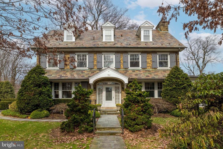 A True Gem in Highly Sought-After Baederwood! Nestled on over half an acre, this exceptional three-story Colonial, constructed of Chestnut Hill fieldstone and complemented by a classic slate roof, offers timeless elegance and enduring craftsmanship. Built in 1925 by John Hohlefelder—the largest stone, brick, and block contractor in the region at the time—as a gift for his wife, Amelia, the home reflects both extraordinary workmanship and thoughtful design. The oversized, private lot provides a true estate-like setting with ample space for a pool and outdoor entertaining. Step into the airy entry hall, where high ceilings, exquisite millwork, gleaming hardwood floors, and meticulous attention to detail immediately impress. The gracious living room features a stunning fireplace adorned with unique and historic Mercer tiles, custom built-in bookshelves and oversized windows with deep sills that fill the room with natural light. Just beyond, a bright tiled four-season room showcases an exposed stone wall, gas fireplace, and French doors opening to a beautiful bluestone patio. The elegant dining room, complete with a built-in corner cabinet, offers an inviting space for gatherings.The updated kitchen features premium appliances, granite countertops, seating, and an adjacent butler’s pantry with abundant cabinetry. A well-appointed laundry and mudroom with built-in storage and access to the oversized two-car garage, along with a convenient powder room, complete the first level. A gracious staircase with polished dark wood handrails leads to the second floor. The primary suite offers a spacious bedroom with generous closet space and a beautifully updated bath featuring a walk-in shower and radiant heated floors. The second bedroom includes an adjoining third bedroom—ideal for a den, office, or potential in-law suite. An updated Jack-and-Jill bath, a fourth bedroom, and a rear staircase complete this level. The third floor is filled with charm and character, highlighted by distinctive curved windows, two additional bedrooms, a cedar closet, walk-in attic, and a bright full bath. The unfinished basement offers exceptional versatility, including a wine room with tasting table, potting room, built-in work area, abundant storage, and Bilco doors providing easy access to the patio. Outside, the beautifully landscaped grounds are truly a gardener’s dream, showcasing mature trees and thoughtfully designed plantings throughout the property. Additional highlights include a bluestone patio, elegant walkways, and stately pillars with curbing and stone walls that enhance the home’s timeless appeal. Additional amenities include high-velocity central air and a recently installed generator. Ideally located in a wonderful neighborhood, this beloved home is within walking distance of Abington Middle School, Abington Senior High School, and Baederwood Park, and is close to restaurants, shopping, and transportation. Located in the award-winning Abington School District. A truly special property and a rare opportunity.