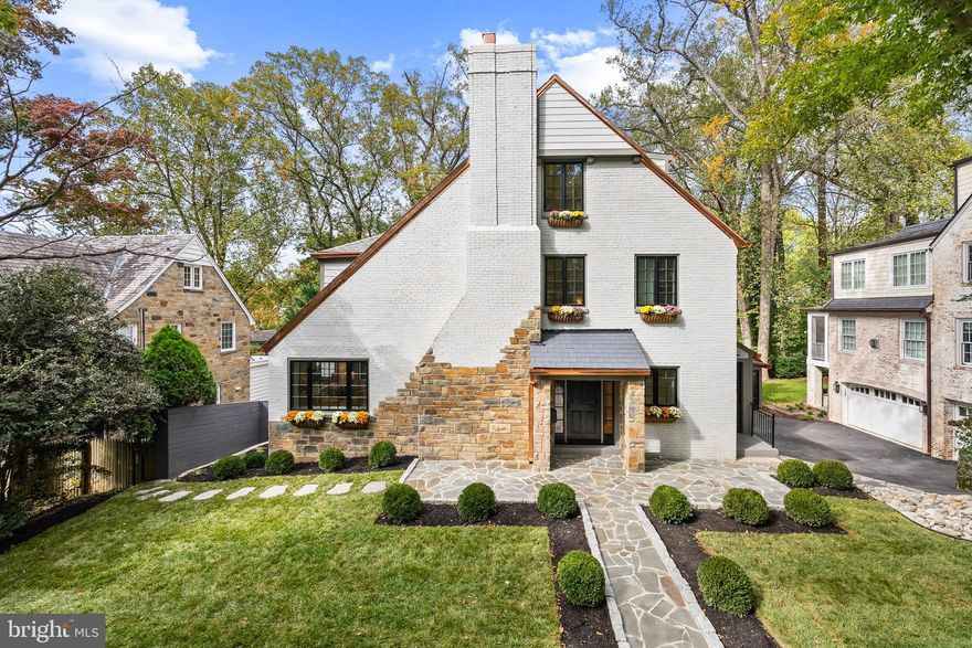 Old world charm, contemporary design and modern amenities come together seamlessly in Dilan Home's newest project, 4949 Quebec Street NW.  Located on one of Spring Valley's most desirable streets and wooded locations, this brick and stone Tudor inspired home has been lavishly updated and re-imagined. Undeniable curb appeal, lush landscaping and a blue stone hardscaped walk welcome you into the homes sheltered portico. Inside is an expansive layout which includes four fully finished levels all done in wide plank European White Oak floors and high end on trend solid metal fixtures. The main level features a large formal living room with wood burning fireplace, separate side entry with coat room, formal banquet style dining room, family room with steps down to a gourmet eat-in kitchen with quartz island, walk-in pantry and direct access to an over-sized elevated deck with commanding views  of the rear garden and wooded valley beyond. An expanded double width staircase leads upstairs to the 2nd floor with its three full bedroom suites including the owners suite with rear wooded views, walk-in closets and a spa like bathroom.  The upper most floor features a spacious landing area and two additional bedrooms serviced by a hall bathroom. The lower level comprises the entire footprint of the house and has a separate Au-pair suite with it's own private laundry,  recreation room, rear gym/office with french door access to a covered patio and a utility mudroom adjacent to the single bay garage. The walkout lower level has ample light and provides immediate access to the manicured rear yard with stone retaining walls, planters, extensive hardscaped patios and a level grass lawn. 4949 Quebec Street represents the epitome of understated modern elegance in a restored and architecturally appealing facade that is still walking distance to the amenities of Spring Valley.