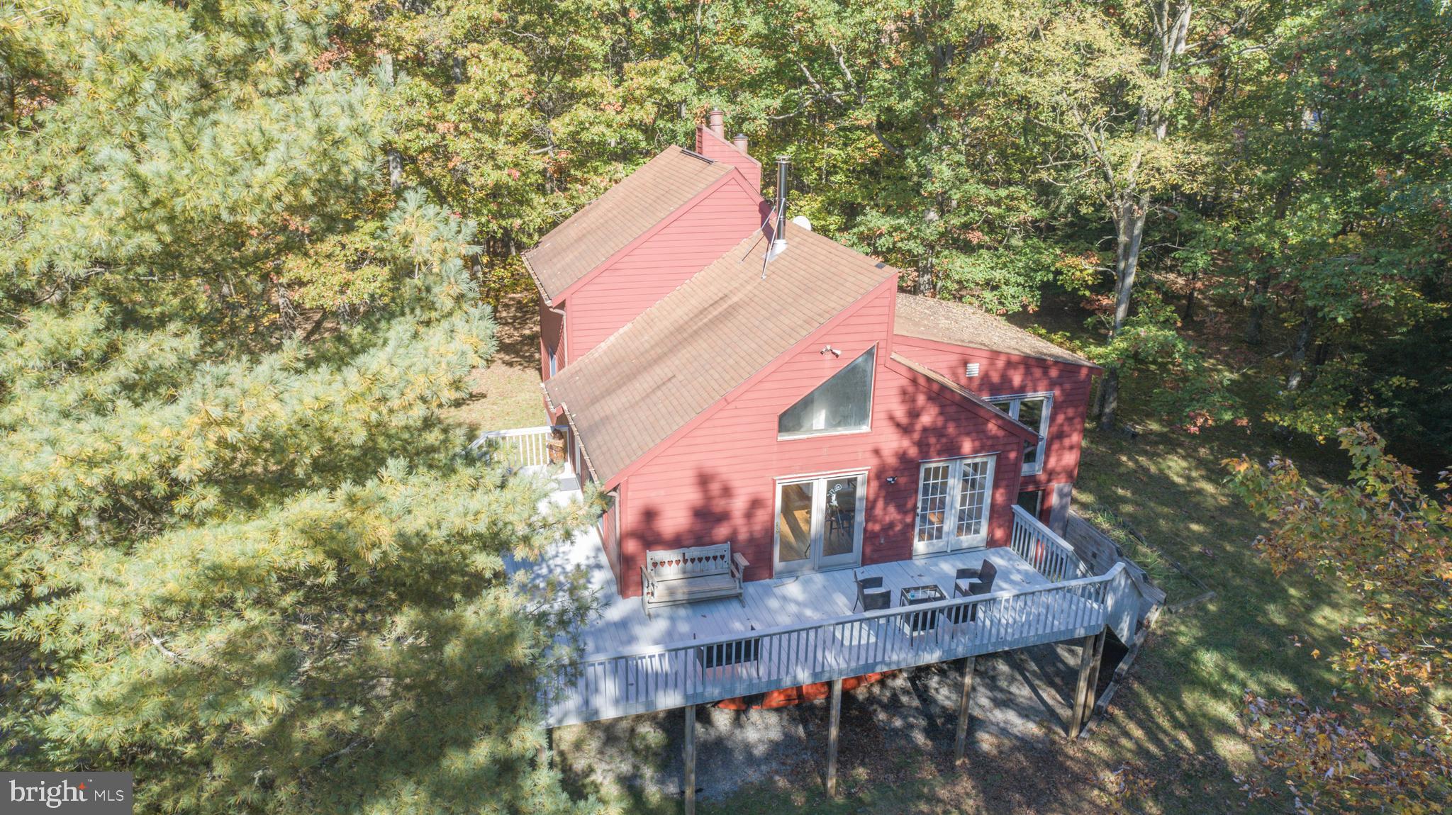 Charming Lake Access Chalet in sought-after Sky Valley! This 3 bedroom, 2 1/2 bath home is nicely set against the surrounding trees offering serenity and easy living on almost 1.5 acres. The spacious living room, featuring wood floors, open beam vaulted ceiling, and woodstove, flows into the dining area with access from both rooms to the large side deck. The vaulted ceiling and lots of windows make for bright and airy main level living and dining areas. The large country kitchen has a natural flow for cooking and entertaining and is just steps to the dining table. Also tucked away on the main level is a quaint side seating area overlooking the beautiful back yard and the trees and leads into a fun game room for family and friends. A guest bedroom and a cute bunkroom share use of another full bath on the main level. The main ensuite, upper-level bedroom, offers privacy. The lower-level family room, with fireplace, provides another versatile space for entertainment and relaxation. Additional living space on the lower level includes a recreation room with hot tub, a convenient half-bath, and laundry room, along with an integral 2-car garage. Enjoy the Sky Valley Community offering lake access, private boat launch ramp, swimming area with sandy beach, children's playground, basketball court, and fishpond. Home ownership includes the possibility of leasing a boat slip via the Sky Valley Community Boat Slip and Marina Policy. Find a new lifestyle and renewed inspiration in this private lake access retreat!