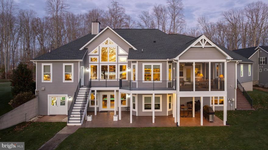 Presenting 95 Olive Branch Court—an extraordinary tribute to waterfront luxury in Noah’s Landing on the private side of Lake Anna. Framed by sweeping, unobstructed water views and unforgettable sunsets, this custom-built craftsman masterpiece was constructed in 2017 by Spartan Homes and is perfectly positioned on a .75-acre lot with approximately 150 feet of pristine rip-rap-protected shoreline, a private boathouse, and deep, calm waters ideal for year-round lake enjoyment. Offering over 5,000 square feet of impeccably designed living space, this home delivers a seamless blend of refined sophistication and relaxed lakeside living. With 5 expansive bedrooms, including a main-level bedroom suite, and 4.5 beautifully appointed bathrooms, the home provides luxurious accommodations for both everyday living and hosting guests. The primary suite showcases a tray ceilings, a large walk-in tiled shower, double vanity, and his-and-her walk-in closets with custom shelving. Throughout the home, refined architectural details abound—vaulted and 9’+ ceilings, rich hardwood flooring, and walls of glass that flood the interior with natural light while framing breathtaking lake views. The stunning gourmet kitchen features granite countertops, stainless steel appliances, breakfast bar seating, a breakfast room with bay window, and an exquisite custom bar—perfect for entertaining. Additional highlights include an integrated Sonos sound system, water softener system, stone gas fireplace with built-in cabinetry, and thoughtfully designed living spaces that flow effortlessly indoors and out. The massive finished basement expands the living space even further, offering a mini kitchen, family room, recreation area, two additional bedrooms, two full baths, and ample storage—ideal for extended stays or entertaining. Outdoor living is equally impressive, featuring a composite deck overlooking the lake, a large screened-in porch, custom exterior lighting, and a walkway leading directly to your shoreline and boathouse. Completing the property is an impressive (1,228 square foot) 4-car attached garage with a 7,000-lb lift and separate workshop room, paved driveway, lake-fed irrigation system with 12 zones, and high-speed fiber internet through Firefly. This exceptional waterfront estate offers an unmatched lifestyle in a prime Lake Anna location—where luxury, comfort, and unforgettable lake memories come together.