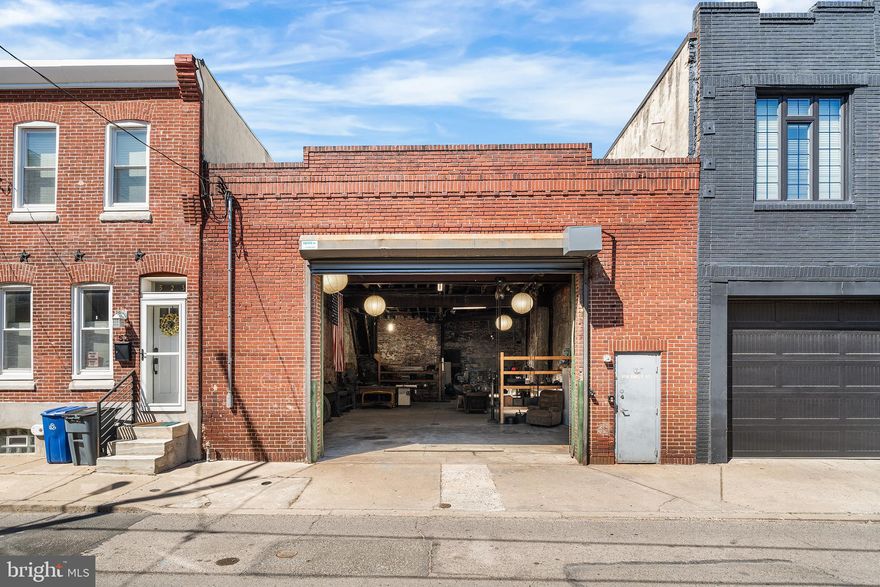 519–21 Emily St is the double-wide South Philly garage you’ve been hoping would hit the market. Behind a classic brick facade, this expansive, light-filled space reads more like an industrial studio than just another garage. Inside, soaring ceilings, exposed brick, and heavy timber and steel beams create a raw backdrop, while oversized skylights pour in natural light - giving the entire interior an unexpectedly airy feel. Zoned RSA-5, the property is best suited for personal use - ideal for a woodworker, fabricator, artist, or collector in need of serious space to create, store, and spread out. For buyers with vision, it also presents a compelling opportunity to explore a unique residential conversion. Buyers may also investigate potential zoning changes for alternative uses; any plans are subject to city approvals. The double-wide footprint is rare, offering room for multiple vehicles, large equipment, or flexible work zones. Toward the rear, a partial second-floor hayloft spans roughly a quarter of the building, featuring warm wood plank walls, and access to the newly installed roof - perfect as a storage area, studio perch, or future build-out with character to spare. Extensive upgrades mean the heavy lifting is already complete. Improvements include a new electrical service with in-slab conduits and updated outlets throughout, a brand-new 8” reinforced concrete slab with integrated drainage and floor drains, new stairs to the loft, and a new rubber membrane roof over both the main structure and loft. Skylights enhance the bright, open feel, and the garage door was replaced at the end of last year. While the property has not previously had gas service, a line has been extended to the exterior for future hookup. Whether you’re housing a car collection, scaling up a craft, or designing something entirely your own, this is a rare opportunity to own a flexible, character-rich space in South Philadelphia.