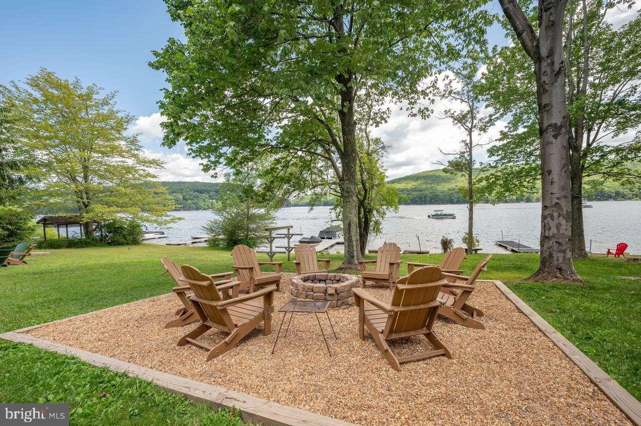 CUSTOM-DESIGNED DEEP CREEK LAKEFRONT LOG HOME ***Fully Furnished 5BR w/ Dock, Hot Tub & Fireplaces*** Welcome to Morningside Lodge, a true waterfront gem nestled along the shores of Deep Creek Lake. This five-bedroom, four-and-a-half-bath custom Mountaineer Log Homes lodge offers a seamless blend of mountain elegance and modern comfort. Situated on a gently sloping lot with direct lakefront land, the property features a Type A dock, composite deck, hot tub, and a custom-built fire pit—all perfectly positioned for year-round mountain living or luxurious weekend escapes. The main level of Morningside Lodge includes a master bedroom with large en-suite bathroom, perfect entryway room for all of your ski gear, gourmet kitchen with breakfast peninsula, and a large great room with oversized Anderson sliding doors, 10-person custom-built dining table, floor-to-ceiling windows filling the room with natural light, and a stone fireplace adding cozy charm in the living space. Upstairs, enjoy the loft overlooking the great room with scenic views of Deep Creek Lake, along with two master bedrooms with en-suite bathrooms. The lower level is the perfect place to play, with a thoughtfully-designed gathering space, pool table, wet bar, and two additional bedrooms with a full bath. Sold fully furnished and meticulously maintained by its original owners, the home has been professionally stained and sealed in 2023 and includes public water/sewer, propane heat, and a grinder pump system. Located on Garrett Highway in the heart of Deep Creek Lake, this property offers proximity to the area’s top attractions, including a short 5 minute drive to WISP Resort, restaurants, and more! No HOA. Don’t miss the chance to own one of the lake’s premier homes—this is lake life at its finest. Proven rental history will be provided upon request for Morningside Lodge!
