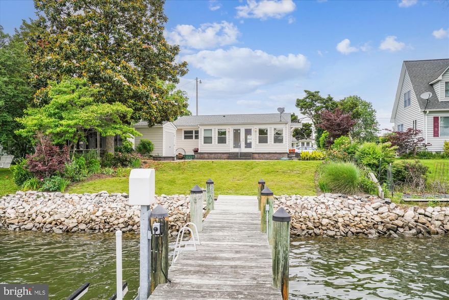 Renovated kitchen boasting granite counters and white cabinets. Open floorpan with extensive patio pavers to make a beautiful sitting area to take in the views of Patuxent River.  New HVAC unit installed Aug 2025! DIRECT RIVER ACCESS with your private pier with electric and lift. Perfectly appointed two bedrooms with two full bathrooms, large and open great room off the kitchen with a large and open great room off the kitchen with unobstructed water views with your own private pier. •••Please note, the detached garage with screened in porch belongs to the neighbors home. It is not on this property, please do not enter••• The shed that opens to the patio does belong to this home.