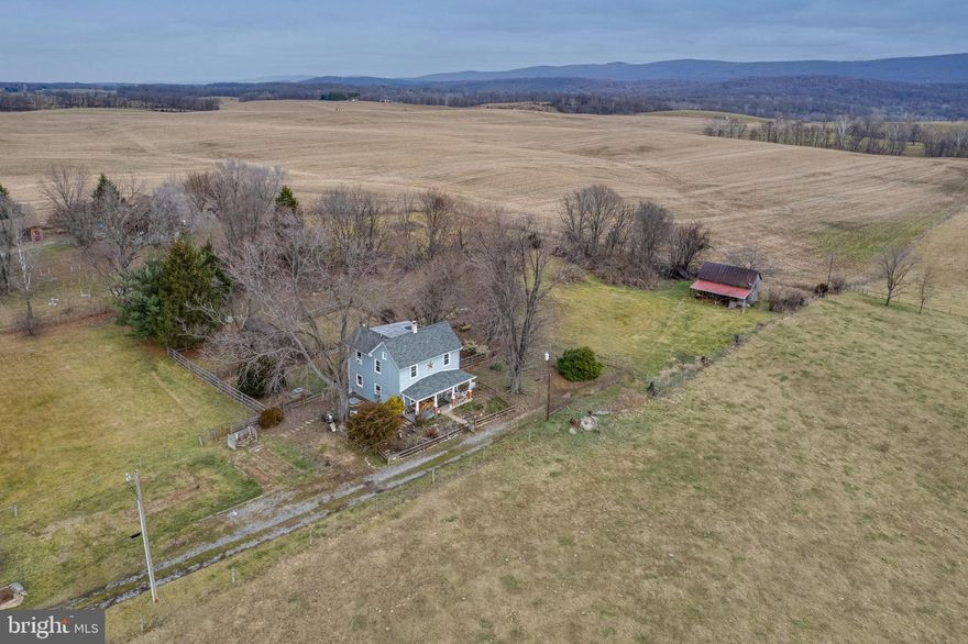 Bring your horses. This one-of-a-kind colonial has been tastefully updated with modern conveniences while maintaining the historic charm with period hardwood floors, exposed beams and stairwell. Upgrades in recent years include the plumbing and electric, newer roof, gutters, soffit, facia, windows, wood stove, hot water heater, well pump and sump pump. The second floor has a large master bedroom with vaulted ceiling and bathroom that needs to be finished but already has plumbing and electric and ready for drywall and finishes. If you're looking to live off the grid but not far from civilization this is the perfect location. This farmette style property offers a lot of privacy at the end of a private lane and includes large barn for equipment or animals and greenhouse (needs a new covering) both of these locations have electric and water. There are 5 separately fenced areas for animals and crops and a New Zealand 6-strand electric fence with transformer. Antique gas pump, outhouse and tool shed are unique to this property.  Relax on the front porch and enjoy the panoramic view of the surrounding mountains and rolling hills of WV. Field in front of the house is protected and will remain farmland.  Cash, conventional or renovation loan only.  Call today.