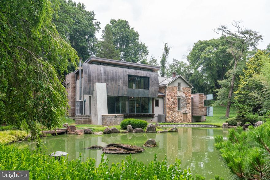 Art Collector’s Private retreat situated on 3 acres and focused on a formal Japanese garden and spring-fed Koi Pond.  Nestled in a serene glade between Middletown and Gradyville Roads and set back from both is a perfect example of architectural prowess. This exceptional residence stands as a testament to the visionary expertise of award winning architect, Wesley Wei for which he won the AIA Gold award.  Crafted from a blend of old stone, poured concrete, and cedar wood, the home is a masterful fusion of materials, showcasing a seamless integration with its natural surroundings.  The home is comprised of an original 700sf pitched roof farmhouse which connects to the kitchen, a small, narrow volume floating on a concrete plinth and which counterbalances a voluminous living room, gallery space where the main bedroom floats above affording a sweeping view of your own private formal Japanese manicured garden and pond.  Corten Steel, lead coated copper, and western cedar clad the new additions, each with their own identity and style while respecting the simplified form of the original structure.  Enter the home through a custom steel full swing door into an intimate foyer.  This space gives way to an 18’ high gallery space opening to the main living room. To the left, the dining room inhabits the former farmhouse with reclaimed pine flooring and an original fireplace. The small kitchen extension projects from the dining room and boasts top-of-the-line stainless steel appliances, including a Subzero refrigerator effortlessly blending with the pristine Bulthaup cabinetry.  Each of the spaces is joined together by steel and glass enclosures creating window bridges affording views of the pond and surrounding property. A minimalist steel staircase ascends to the second floor primary suite, a wide open space floating above the living room.  The loft-like bedroom is open to the gallery and living room below and affords views of the pond in front.  In the full bathroom, intricate mosaic details adorn the glass enclosed shower, set against a backdrop of rich dark slate walls. The bathroom is flanked by two smaller rooms which could be bedrooms, the last owner used them as office and walk-in closet. There is an artesian well below the farmhouse portion which provides all the home’s water needs.  Completing the ensemble of buildings is a separate four-car garage with a motorcycle lift, featuring an artist's studio above and providing a creative sanctuary for inspired endeavors. This residence is your creative retreat which transcends the ordinary, offering a harmonious blend of artful design and serene living.