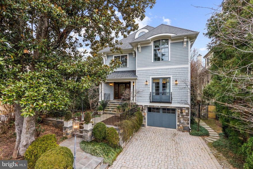 Set back on a picturesque, tree-lined street in the coveted Berkley neighborhood of Washington, D.C., this exceptional residence, masterfully designed by Chryssa Wolfe of Hanlon Design and Build, offers a sophisticated blend of classic architecture and contemporary living.
A graceful stone staircase leads to a welcoming portico framed by lush landscaping and blooming hydrangeas. Inside, a formal foyer opens to tall ceilings, arched doorways, and a thoughtfully designed floor plan that flows effortlessly throughout the main level. The living room features intricate millwork, custom built-in shelving, and expansive windows that fill the space with natural light. The adjacent dining room shares these elegant details and a fireplace, offering an ideal setting for gatherings. The kitchen has been designed with both form and function in mind. Outfitted with top-of-the-line appliances including a six-burner range with hood, it features an oversized center island, built-in banquette seating, and refined custom moldings. The kitchen flows into a light-filled family room with coffered ceilings, a marble fireplace, and French doors that open to a private backyard terrace. A powder room located off the living room adds convenience and completes the main level.
Upstairs, the second level offers four generous bedrooms, including a luxurious primary suite with a large walk-in closet featuring a center island. The spa-inspired primary bathroom includes dual vanities, a soaking tub, stone finishes, and a frameless glass shower. Each additional bedroom on this level includes an en-suite bathroom, substantial closet space, and large windows. This floor also showcases beautiful built-in shelving, detailed millwork, and a full laundry room.
The light-filled third level adds flexible living space with large rooms and high ceilings. There are three generous rooms that can be used as bedrooms, offices, wellness spaces or a family room. There is also an additional full bathroom on this level.  
The fully finished lower level is designed for both entertaining and extended-stay living. This level features an oversized recreation room with a gas fireplace, guest or staff bedroom with an en-suite bathroom, an additional half bathroom, and a kitchenette. A well-equipped mudroom includes a second laundry area with sink and cabinetry and provides interior access to the oversized garage. There is also an additional surface parking space and a separate entrance that leads from this level to the backyard.
Outdoors, the professionally landscaped backyard features a heated pool, automatic cover, cascading waterfall, and flagstone surround. A terrace with a built-in outdoor grill and multiple seating areas provides an ideal setting for year-round entertaining. Beyond, the fully fenced yard extends to a private putting green, offering a unique and playful outdoor retreat.
This prestigious and convenient neighborhood offers walkable access to neighborhood restaurants, parks, and the C & O Canal path. Georgetown, Downtown D.C., Reagan National and Dulles Airports are easily accessed as well.  This offering provides exceptional privacy, thoughtful design, and unparalleled livability in one of Washington’s most sought-after communities.