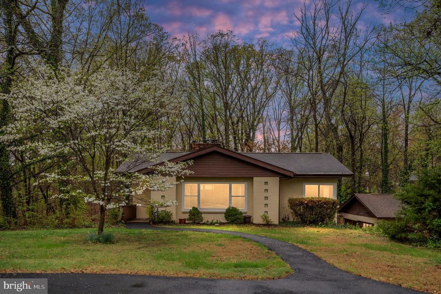 This is a mid-century MARVELOUS home you will surely want to see! Sitting on over a half-acre lot, nestled amidst a sheltering family of trees, this charmer will win your heart before you even walk inside. It features a paved circular driveway in front of the home, as well as a crushed stone driveway in front of the detached garage, so there is PLENTY of parking. There is a small front porch by which you enter the home, walking into the spacious living room. The living room features a vaulted ceiling, a massive brick fireplace (woodburning), custom built-in bookcase, track lighting, and hardwood flooring. The dining area is just off the living room, and also boasts those wonderful hardwood floors. The kitchen is next to the dining area, and offers a breakfast bar that opens out into the dining room, a custom brick backsplash, 2 custom pantry / cabinets, a gas stove, and LVP flooring. There is another pantry just outside of the kitchen, as well. Next, you’ll find a full bathroom, the primary bedroom (with dual closets and hardwood floors), and bedroom #2 (also with hardwood floors). If you take the stairs just off the kitchen, you’ll find the door to the fantastic deck at the landing. If you go down the rest of the stairs you will enter the full and finished basement. There you will find a rec room with a stone fireplace and wood stove insert, a 3rd bedroom, a bonus / flex room (could be a NTC 4th bedroom, office, workout room, etc.…), a laundry room, and a full bath (with double sinks, and custom tile work from top to bottom). You can walk out into the fenced backyard from the basement, and from there you can access the deck or venture down the path beyond the fence line to enjoy the fire pit and hammock areas at the back of the property. It is very private with a wonderful, woodsy feel. You can also quickly access the garage side door, which is just a few steps beyond the fence gate. The garage, which has electricity and is heated, has room to park a car, as well as lots of storage space. This delightful home with its mid-century charm has it all: over 2,000 FSF of indoor living space, plus outdoor living spaces (like the huge 260 SF deck overlooking the beautiful tree line, the expansive backyard which includes the hammock and fire pit areas, and the cozy front porch), a fantastic garage, and a convenient location! In fact, this home is only about a mile to Base Quantico’s front gate, about 2 miles or less to both I-95 and the 234 Commuter Parking Lot,  just 20-25 minutes to various marinas, only 25 minutes to Potomac Mills, and  just 30 minutes to Spotsylvania Towne Centre and Central Park.