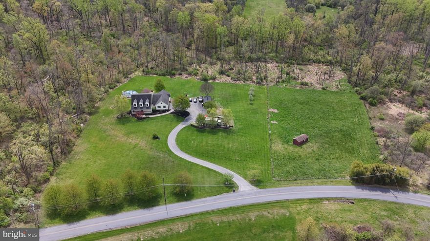 ***ALL OFFERS DUE  Thursday, May 7th at 12 pm.*** Some people dream of a life where the morning sounds like birdsong, the view from every window is pure nature, and the land beneath your feet is truly your own. 725 Buttermilk Road is that place.
Tucked peacefully along a quiet country road yet minutes from everything the Lehigh Valley offers, this 5-bedroom, 2.5-bath Cape Cod sits on over 10 private acres enrolled in Act 319 (Clean & Green). Raise an animal, tend a garden, harvest your own fruit trees, explore woodland trails, or simply exhale. This land welcomes all of it.
A sweeping curved driveway, blooming red Japanese maple, mature landscaping, and a classic covered front porch set the tone the moment you arrive. The attached 2-car garage, shed, and red run-in shed with fenced pasture are ready for whatever hobby or homestead vision you bring.
The first-floor primary suite offers effortless single-level living with luxury vinyl plank flooring, rustic barn door sliders, and two walk-in closets with built-in shelving. The en suite bath features a soaking jetted tub with peaceful views, walk-in shower, and double vanity.
The generous kitchen is built for real, purposeful living — dark espresso cabinetry to the ceiling, a farmhouse stainless apron sink, a soapstone-topped island, dual wall ovens, cooktop, stainless refrigerator, and recessed lighting throughout. The adjoining breakfast nook with abundant natural light and a built-in mudroom keep everyday living seamless and organized.
The great room impresses with a shiplap-style wood accent wall, custom built-in shelving, luxury vinyl plank floors, and oversized windows framing views of blooming redbud trees and the spacious back yard.
The full basement — insulated, plumbed, and featuring a wood-burning stove on a circular paver hearth — is ready to finish as a workshop, rec room, gym, or additional living space.
Fruit trees, fenced pasture, mature woodland, and open sky — all in the Wilson Area School District, minutes from Hellertown and Bethlehem. Schedule your private showing today!