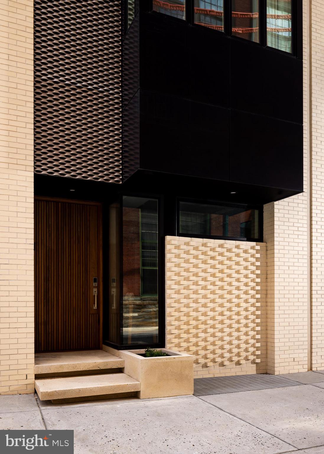 Designed by the renowned Philadelphia-based Atrium Design Group, 1640 Carlton St. stands as a testament to modern architectural magnificence. Located in Logan Square, just steps from some of the country's most celebrated museums, this 28' wide, 4-bedroom, 7-bathroom townhome offers unparalleled luxury and meticulous attention to detail in every aspect of its design. Notable features include 3-car garage parking, 3 separate private outdoor spaces, an elevator, a double-height living room, and unique smart tech features. You will be blown away by first impressions, starting with a façade that boasts intricate modern brickwork, custom metal paneling, numerous window arrays, and a floating stone patio. A stunning solid walnut pivoting door opens to the foyer, where a first-floor bedroom suite awaits on your right. This suite features custom built-in closets, a corner window, and an en-suite bathroom complete with elegant wall tile, a wall-mounted toilet, and a glass sliding shower door. This level also includes access to the garage. As you ascend to the main living level, you'll notice a powder room that’s a true work of art, featuring custom slot wall paneling, a backlit stone accent wall, a black pedestal sink, and a ceiling-mounted water drop faucet. The main living space is both striking and minimalist, with a custom European kitchen that includes a massive center island fitted with Super White Quartzite, a matching backsplash, top-of-the-line Wolf coffee maker, double wall ovens, a cooktop with integrated knobs, a drawer microwave, a panel-ready Sub-Zero refrigerator, a pot filler, and lava pendant lights. Adjacent to the kitchen is the living room, an extravagant area with a double-height ceiling, cove lighting, and a giant gas fireplace adorned in porcelain. A massive slider opens to a balcony with pedestal pavers. This level also features a formal dining room, complete with a butler’s pantry and a 98-bottle glass wine vault. Additional details include large format floor tiles and linear slot diffusers. Take the elevator to the next level, where an open mezzanine overlooks the living room. A custom wood panel wall conceals a hidden full bathroom, highlighted by stunning textured wall tile and a Porcelanosa Solid Surface free-floating vanity. This level also includes another bedroom suite with a large window array, a walk-in closet, and another beautifully appointed en-suite bathroom. Continuing up the custom floating staircase, you'll reach the primary bedroom level. Here, you're greeted by a massive wet bar with stone countertops and a beverage cooler. Behind a hidden door lies a laundry room. The primary bedroom suite is nothing short of extravagant, with towering ceilings and a 10-foot-tall Pella sliding door leading to a private balcony. A walk-in closet features an island wardrobe and custom built-in organizers with glass doors. Pocket doors lead to the lavish, spa-like primary bathroom, which includes a spacious steam shower, a Porcelanosa soaking tub, and a massive double vanity with wall-integrated Brizo faucets. An additional half bath is located at the top of the stairs, just before you reach the rooftop terrace. With over 800 square feet of outdoor living space, this area is unparalleled, featuring two louvered pergolas, heat lamps, an outdoor kitchen with a stainless steel grill and a luxurious Bradford hot tub. Enjoy unobstructed views of the city as you entertain guests. The lower level of this urban estate is reminiscent of a high-end hotel lounge, with a custom contemporary bar and integrated sound system, perfect for hosting endless parties. Additionally, this level includes a fitness room with wall mirrors and a full bath. The home holds endless features, including Pella windows wired for automation, heated floors, multiple HVAC zones, sound system and more. It is located in NOVO, a gated community just minutes away from some of Philly's top restaurants and cultural institutions. A WORK OF MODERN ART!
