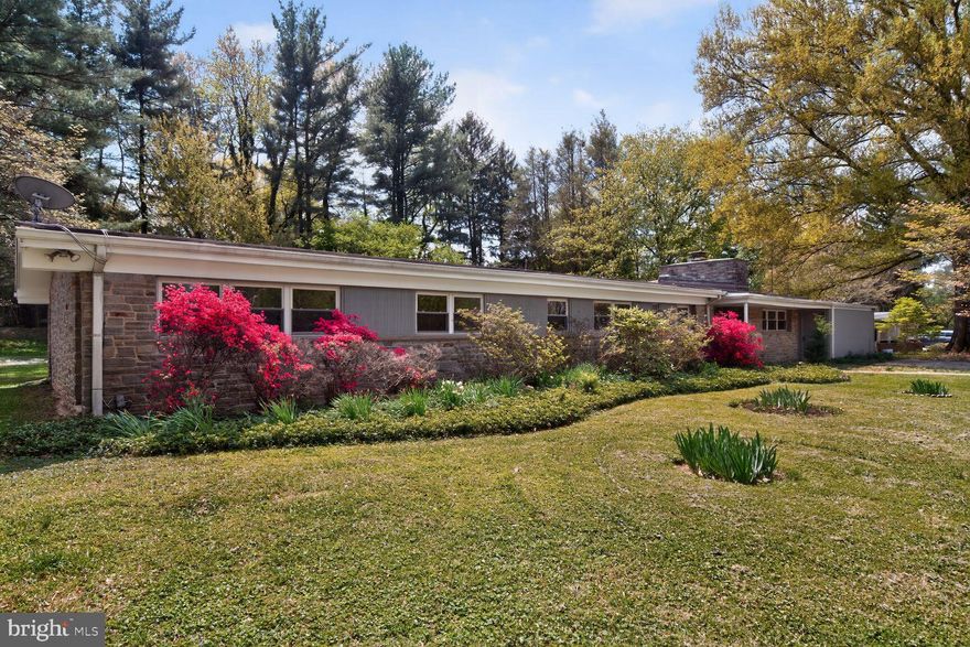 Tucked into the sought-after Stevenson Village community, this beautifully maintained one-level mid-century ranch offers effortless living with timeless design. Set on a generous, .65-acre landscaped lot, the home’s long, low profile, stone façade, and clean rooflines create a striking first impression—perfectly capturing the essence of mid-century architecture.

A charming stone walkway leads to the welcoming entry, framed by mature plantings and a picturesque flowering tree, while the home’s expansive front elevation hints at the spacious interior within. Blending inside and out, the entrance continues the stone from outside and slate flooring. An original mid-century modern cabinet/room divider completes the entrance area, which also includes modernist storage cabinets for coats and shoes.

The sprawling rancher features five bedrooms, two full bathrooms, and one half bathroom, providing exceptional flexibility for modern living, whether for family, guests, or dedicated work-from-home spaces.

The layout offers expansive living and dining areas filled with natural light, designed with an easy flow ideal for both daily living and entertaining. True to its mid-century roots, large windows bring the outdoors in, while the surrounding greenery provides a serene and private backdrop.

The foyer enters into the expansive living room with luxury vinyl flooring and walls of glass overlooking the backyard. Just off the living room is the 5th bedroom or office space with full stone wall and fireplace. The bright kitchen features newer stainless-steel appliances and opens to the dining room with custom built ins and the sun room area.

The main bedroom hallway features wood floors and includes four bedrooms, including the primary suite with custom wardrobe area and high-end bathroom with double sinks, shower and tub. The second full bathroom has two sinks and large glass-enclosed shower.

The original garage and/or carport was converted into a large shop area or storage space.

Stevenson Village, just north of the Baltimore Beltway, is one of the region’s most distinctive enclaves of mid-century modern design. Developed primarily by Gordon E. Sugar from the 1940s through the 1960s, Stevenson Village is often compared to iconic modernist communities such as Hollin Hills—known for homes by Charles Goodman—and Carderock Springs, designed by Edmund Bennett and his partners. With its low-slung rooflines, expansive glass, and seamless integration with the natural landscape, Stevenson Village feels as though it could just as easily be found in Los Angeles or Palm Springs.

Through his company, Gordon E. Sugar Inc., Sugar developed several hundred homes in the Stevenson Road area, creating a cohesive architectural vision defined by nearly flat roofs, walls of glass, and a deep connection to the surrounding landscape—an enduring legacy that continues to define the neighborhood today.

The home’s level yard offers endless possibilities for outdoor living, gardening, or future enhancements, all within a peaceful, established setting just moments from shopping, dining, and major commuter routes.
