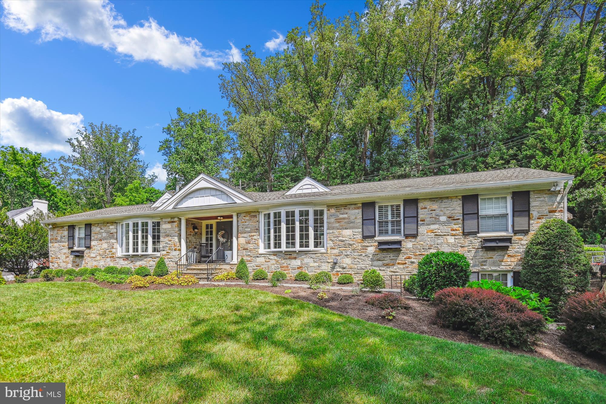 Sophisticated Stone Rancher in coveted Woodbrook, Baltimore County! Nestled in a quiet cul-de-sac, this stunning stone rancher offers a rare opportunity to enjoy the best of both privacy and convenience, with walkability to Lake Roland, two coffee shops, and Eddie’s Market. Boasting 4–5 bedrooms and 3 full baths, this spacious home spans a total 4,819 square feet of finished living space, offering flexible layouts for any lifestyle. The main level features a sun-drenched family room adjacent to the eat-in kitchen, which is well-equipped with ample storage and a cozy gas fireplace. The living and dining area is anchored by a beautiful stone fireplace and a bay window, allowing natural light to flood the space. A home office and the primary suite with generous closet space are thoughtfully separated from the children's wing, which includes three additional bedrooms. The lower level has been completely transformed, offering a versatile living space that includes a mudroom with a second laundry area, a potential au pair suite, or additional family space. This lower level also includes a kitchenette, full bath, bedroom, and family room with another stone fireplace.
The professionally landscaped yard is a true retreat, featuring a saltwater heated pool, outdoor seating area, and fireplace – perfect for relaxing or entertaining. This premier location combines comfort, style, and versatility with tasteful updates throughout, making it the ideal place to call home.