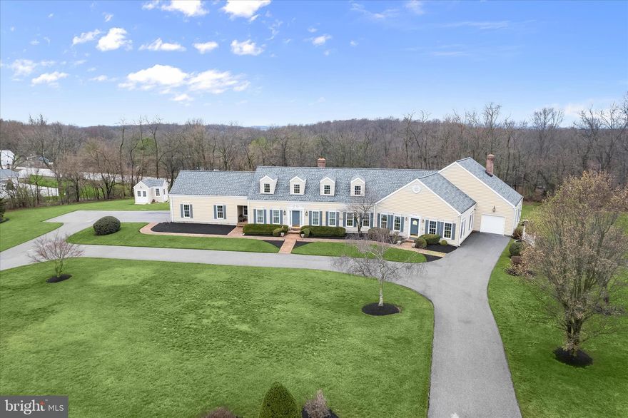 Welcome to this extraordinary estate thoughtfully designed, created, and built by the original owner. Perfectly positioned on the homesite to maximize the surrounding acreage and tree-lined borders, this sprawling property offers exceptional privacy, architectural character, and remarkable versatility with a luxurious main residence and a fully connected two-story guest home. With a combined 6,625 finished square feet this one-of-a-kind property is ideal for multi-generational living, extended guests, or even an income-producing opportunity.
From the moment you enter the gracious foyer, flanked by formal living and dining rooms, the home’s craftsmanship and attention to detail are evident. Reclaimed antique oak hardwood floors, three-piece crown moldings, high ceilings, and generously sized rooms create a timeless elegance throughout the main residence. The eat-in kitchen is designed for both everyday living and entertaining, featuring granite countertops, a center island, a walk-in pantry, and a sunny breakfast room with access to the deck. Just beyond, the inviting family room is anchored by a charming brick-profile wood-burning fireplace. The main-level primary suite offers a peaceful retreat with a walk-in closet plus an additional closet, a beautifully appointed en-suite bath with a glass-enclosed shower, and a connected private office. A laundry room, powder room, and access to the attached two-car garage with polyaspartic floors complete the main level.
Upstairs, three additional bedrooms provide comfortable accommodations, including one with its own en-suite full bath, along with a well-appointed hall bath. The finished lower level expands the living space even further with a second kitchen, recreation room, game area, powder room, abundant storage, and walkout access to the patio making it ideal for entertaining or extended stays.
A gallery connects the main residence to the architecturally striking two-story guest home, offering approximately 2,000 square feet of additional living space that can function as a private in-law suite or established short-term rental. Currently operating as a highly rated Airbnb with an impressive 4.98-star rating, this charming retreat features a dramatic living room with soaring cathedral ceilings and exposed beams, a dining room with a wood-burning fireplace flanked by built-in shelving, a full kitchen, and a light-filled sunroom that opens to a deck and pergola. The main level also includes an en-suite bedroom with a walk-in closet, laundry room, and access to the attached one-car garage. Upstairs, a second bedroom offers two walk-in closets and a luxurious en-suite bath with a soaking tub, glass-enclosed shower, skylights, and an additional walk-in closet. A private entrance with an attached garage and plenty of parking.
Outdoor living is just as inviting, with multiple decks designed for gatherings both large and small, expansive open land ideal for recreation or future expansion, and ample parking for guests. A detached carriage house provides additional storage and flexible workspace for hobbies or projects. Tucked away on a quiet cul-de-sac with no through traffic, yet conveniently located near shopping, dining, wineries, and local attractions that include McDaniel College, CC Farm Museum, Old Westminster Winery, Baugher’s Orchard and Farm, Gettysburg National Park, and Baltimore only 40 miles away. This exceptional estate offers a rare opportunity to enjoy refined country living with unmatched flexibility. Welcome home.
