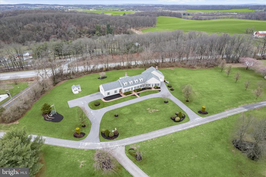 Welcome to this extraordinary estate thoughtfully designed, created, and built by the original owner. Perfectly positioned on the homesite to maximize the surrounding acreage and tree-lined borders, this sprawling property offers exceptional privacy, architectural character, and remarkable versatility with a luxurious main residence and a fully connected two-story guest home. With a combined 6,625 finished square feet this one-of-a-kind property is ideal for multi-generational living, extended guests, or even an income-producing opportunity.
From the moment you enter the gracious foyer, flanked by formal living and dining rooms, the home’s craftsmanship and attention to detail are evident. Reclaimed antique oak hardwood floors, three-piece crown moldings, high ceilings, and generously sized rooms create a timeless elegance throughout the main residence. The eat-in kitchen is designed for both everyday living and entertaining, featuring granite countertops, a center island, a walk-in pantry, and a sunny breakfast room with access to the deck. Just beyond, the inviting family room is anchored by a charming brick-profile wood-burning fireplace. The main-level primary suite offers a peaceful retreat with a walk-in closet plus an additional closet, a beautifully appointed en-suite bath with a glass-enclosed shower, and a connected private office. A laundry room, powder room, and access to the attached two-car garage with polyaspartic floors complete the main level.
Upstairs, three additional bedrooms provide comfortable accommodations, including one with its own en-suite full bath, along with a well-appointed hall bath. The finished lower level expands the living space even further with a second kitchen, recreation room, game area, powder room, abundant storage, and walkout access to the patio making it ideal for entertaining or extended stays.
A gallery connects the main residence to the architecturally striking two-story guest home, offering approximately 2,000 square feet of additional living space that can function as a private in-law suite or established short-term rental. Currently operating as a highly rated Airbnb with an impressive 4.98-star rating, this charming retreat features a dramatic living room with soaring cathedral ceilings and exposed beams, a dining room with a wood-burning fireplace flanked by built-in shelving, a full kitchen, and a light-filled sunroom that opens to a deck and pergola. The main level also includes an en-suite bedroom with a walk-in closet, laundry room, and access to the attached one-car garage. Upstairs, a second bedroom offers two walk-in closets and a luxurious en-suite bath with a soaking tub, glass-enclosed shower, skylights, and an additional walk-in closet. A private entrance with an attached garage and plenty of parking.
Outdoor living is just as inviting, with multiple decks designed for gatherings both large and small, expansive open land ideal for recreation or future expansion, and ample parking for guests. A detached carriage house provides additional storage and flexible workspace for hobbies or projects. Tucked away on a quiet cul-de-sac with no through traffic, yet conveniently located near shopping, dining, wineries, and local attractions that include McDaniel College, CC Farm Museum, Old Westminster Winery, Baugher’s Orchard and Farm, Gettysburg National Park, and Baltimore only 40 miles away. This exceptional estate offers a rare opportunity to enjoy refined country living with unmatched flexibility. Welcome home.