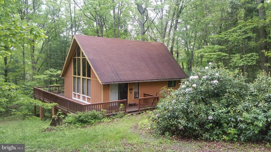 Tranquility and Convenience a rare combination. This comfortable chalet sits just off a paved county lane between Berkeley Springs and Hedgesville WV.  2 bedrooms including the loft, large great room with a fireplace and window wall showing all nature has to offer. The 5.44 acres is beautiful all year long with evergreens, rhododendrons and hardwoods, Put this one on your must see list!