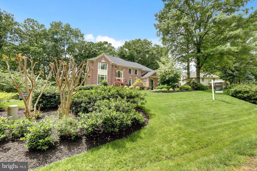 Welcome to this exquisite Stanley Martin estate, ideally situated in the highly sought-after Edgewater community. This beautifully maintained home offers approximately 5,474 square feet of elegant living space, featuring 4 spacious bedrooms, 5 bathrooms, and sits on a manicured 0.58-acre lot with lush landscaping. A stately brick façade and stone walkway lead to a grand two-story entryway with a dramatic curved staircase and open catwalk. Hardwood floors flow throughout the main level, where you'll find a formal living room, elegant dining room, and a private home office with custom built-ins. The step-down family room features vaulted ceilings and a cozy gas fireplace, opening to a bright sunroom with a stone floor. The gourmet chef’s kitchen is a true centerpiece, complete with a large island, Viking range and hood, wall oven, microwave, and a spacious eat-in area. Step outside to the low-maintenance composite deck and enjoy a private, tree-lined backyard—perfect for entertaining or quiet relaxation. Additional main-level highlights include a spacious laundry room with built-ins, granite counters, and tile backsplash, along with double pantries and direct access to the three-car side-load garage. Upstairs, the luxurious primary suite boasts new carpet, hardwood floors, multiple closets, and a spa-inspired bath featuring travertine flooring, dual vanities, a freestanding tub, a multi-jet shower, bidet, and private water closet. Three additional bedrooms with hardwood floors include one with an en suite bath and two sharing a Jack-and-Jill bath. The catwalk and staircase have been updated with new carpet. The expansive walk-out lower level offers versatile living and entertaining space with a gym area, office nook, recreation room, second gas fireplace, wet bar, full bath, and two large storage/work areas. Recent upgrades include a new driveway, new roof, new carpet, freshly painted exterior trim, 16 upgraded windows (installed 6 years ago), and a hot water heater less than 2 years old. The home also features a dual-zone HVAC system (7 and 15 years old). Enjoy nearby walking trails, easy access to scenic Burke Lake and its Golf Center, and proximity to shops, dining, and commuter options including the Burke VRE, Fairfax Connector Bus, Fairfax County Parkway, and Route 123.