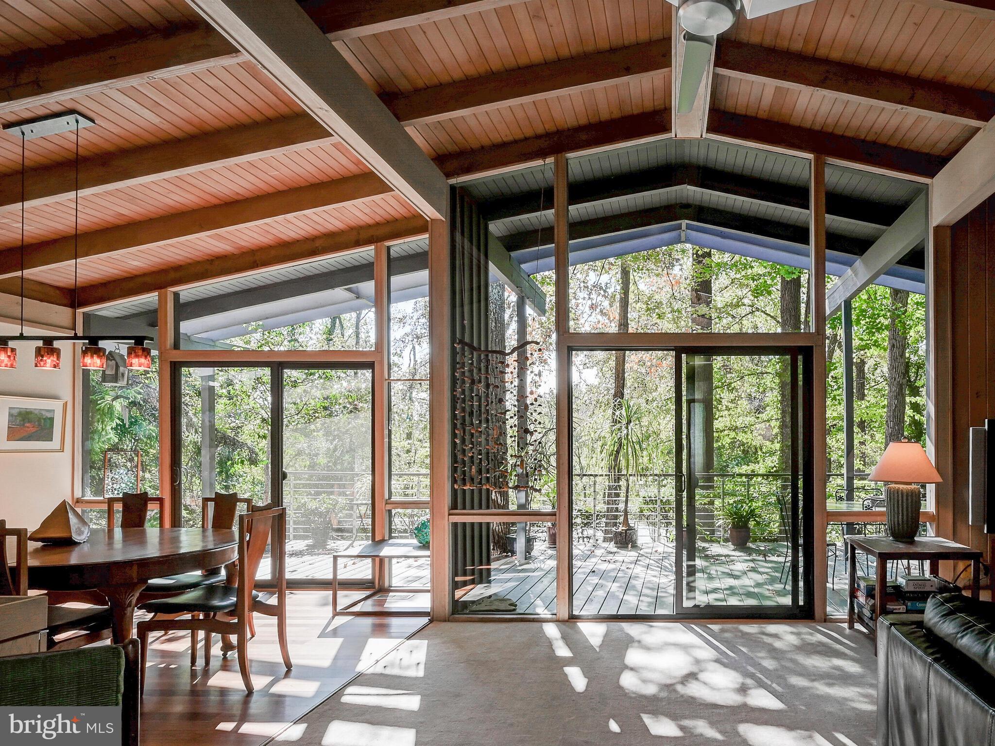 A stunning Mid-Century Modern home with POOL on 1.5 acres with 4BR/ 3.5 Baths, located in The Terraces, a hidden garden-like neighborhood in Mount Washington only minutes to downtown Baltimore. Floor to ceiling glass provides views of the surrounding trees, set within acres of woods- you would never know you're in the city! Open concept living and dining rooms feature a beamed cathedral ceiling, a large stone fireplace and a huge skylight makes this home very bright. Two sliding glass doors in the living and dining rooms open to an oversized deck overlooking the private in-ground pool and trees. The renovated kitchen will delight you with custom fused glass countertops and a large granite island, new stainless appliances including a Wolf cooktop and quiet Bosch dishwasher, and warm solid wood cabinetry. The original MCM kitchen design was retained including the unique glass above the cabinetry and the oversized windows that view a wall of blooming white azaleas in the springtime. The primary bedroom has 13 windows promoting true relaxation amid the peaceful green views, a walk in closet and a jetted tub in the renovated ensuite bath. Two additional bedrooms enjoy oversized windows with beautiful vistas and share a hall bath. An in-home office with original built-in shelving features its own oversized sliding glass door and balcony with wooded views. Brazilian Kempas hardwood floors offer a warm feel in the kitchen, dining room and foyer. The full daylight lower level features a family room with fireplace surrounded by glass and green views. A very large fourth bedroom with room for a living area, offers a private exterior entrance and has a walk-in closet and a full bath with a step-in onyx tiled shower. A kitchenette provides opportunities for use as a private au pair or in-law suite. Step outside the family room to enjoy the hot tub or cool off in the private inground swimming pool ringed by tall trees for ultimate privacy- this is a true Urban Oasis! All of the original MCM design has been retained, while thoughtful updates have been made both indoors and on the exterior, including the roof, gutters, deck, sliding doors, some windows, both skylights, retaining walls and steps to the pool. A special feature is the city/county line that passes through this property making families eligible to attend either school system (buyer to verify). This home has only had three owners and was last on the market in 2006. Will you be the next trustee of this architect-built gem? All original blue prints convey with the home. Furnishings are negotiable.
