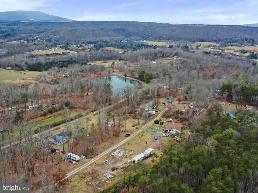 Welcome to Dusk Drive! This is more than just a home and its back on the market ready for its buyer--with an inspection report! Fall in love with this property. The property includes multiple lots, views and amenities. Starting with the home: the open concept living allows for a cozy and spacious feeling! The large kitchen offers a breakfast bar, custom cabinets and plenty of space and storage! The 2 bedrooms offer great space and larger closets! The additional area off the living room can be used as an additional bedroom, playroom, den or office! The home has a new roof, new floors in a few areas and even an above ground pool! Enjoy the view of the private community lake while admiring the  1.25+ Acres which include an updated drain field, 2 above ground hydrants, additional buildings, woods, trails and so much more! This quiet nestled country home is your peaceful getaway while not being far from town and amenities! Bring us an offer! *Want more Acreages? Check out WVHS2005558 and bundle