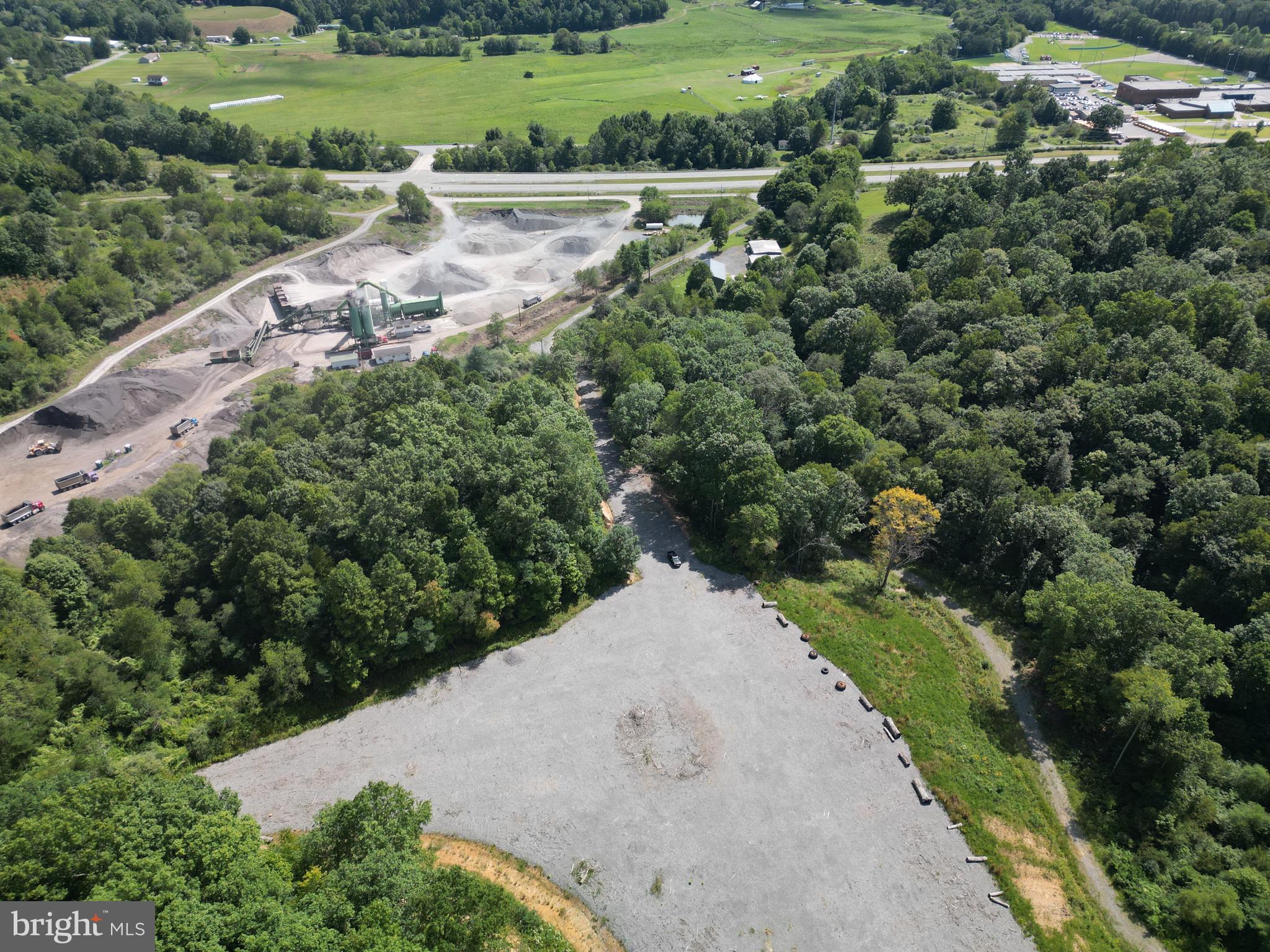 Unlock the potential of this versatile industrial outdoor storage site, ideally situated in the heart of Nicholas County. This approximately 5-acre graveled lot sits within a larger 20-acre parcel and is designed for durability and heavy-duty use, featuring a 1-foot gravel base laid over geotextile fabric and integrated with a stormwater management system—ready to support your operations from day one.
The site includes a gated entrance wide enough to accommodate two trucks side-by-side, ensuring smooth traffic flow in and out. Additional infrastructure includes a truck scale and a small scout house, offering functionality for logistics, material handling, or equipment storage.
Located at 405 Checks Road in Summersville, WV, the property benefits from easy access to key regional routes. WV Route 39 runs east-west through the area, connecting Summersville to Richwood, while US Route 19 offers a direct north-south link to major regional centers such as Fayetteville and Beckley.
This property is nestled in a scenic rural setting with a mix of open land and forest, providing both privacy and natural surroundings—yet it remains just a short drive from town amenities and service providers.
Whether you're expanding your operations or investing in a strategic logistics hub, this property offers the space, access, and infrastructure you need.