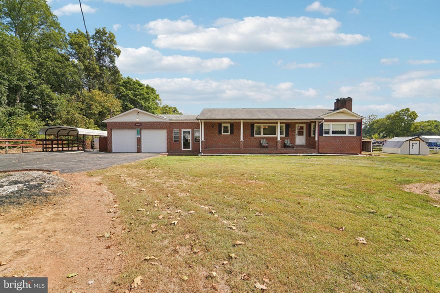 Classic all-brick ranch on a wide lot with tons of usable space and storage. A an extra-wide paved drive leads to an oversized 2-car garage plus a covered carport. Enjoy the welcoming front porch, then step inside to sun-filled rooms with hardwood floors. The living room features a brick fireplace and large picture windows; it flows to a full dining room and an eat-in kitchen with a peninsula/breakfast bar and abundant cabinetry. Comfortable main-level bedrooms, tile hall bath with walk-in shower, and a main-level laundry hook-up that can be easily converted back to the basement. The lower level offers a huge finished rec room—perfect for games or media—plus a wood stove, half bath, utility/laundry sink, storage rooms and workshop space. Between the house and garage is an enclosed breezeway/mudroom with built-in counters/cabinets and a ramp for easy access. A separate three-season room with a brick fireplace adds another great gathering spot and is perfect for entertaining. Outside you’ll find multiple sheds/outbuildings, wood storage, and wide-open yard space with rock outcroppings and pastoral views. Well cared for and ready for your personal updates—bring your hobbies, equipment, and ideas!