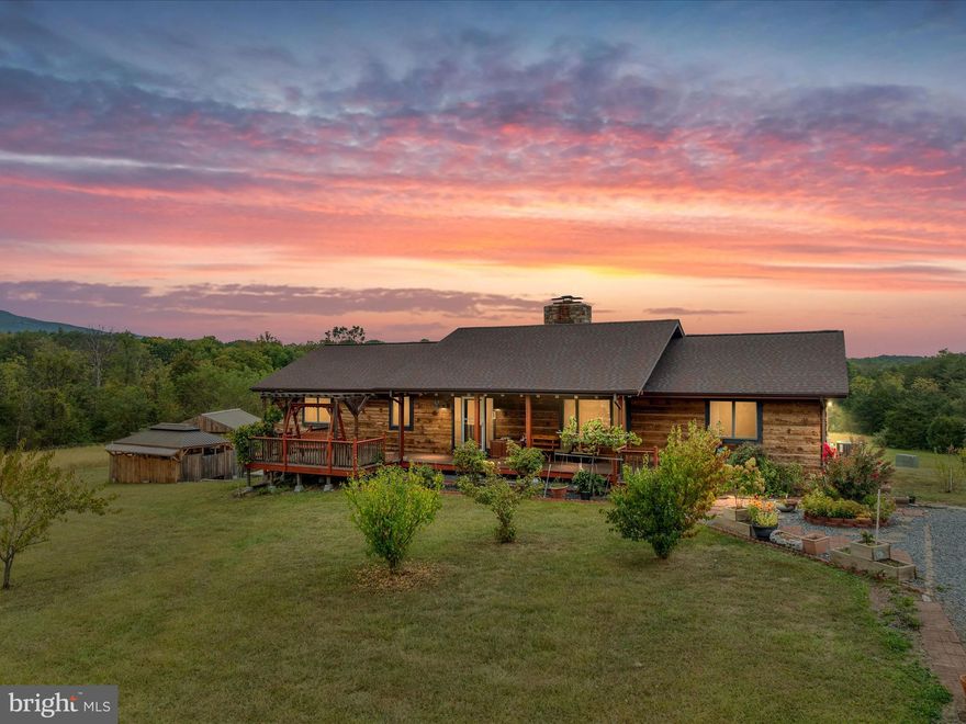 Welcome to your dream retreat—a breathtaking log home nestled on 34 acres of rolling meadows and serene woodlands. Imagine waking up to sunlight coming through the trees, birds singing, and that fresh country smell as you step out onto the porch. Here, tranquility and privacy envelop you, with sweeping vistas of the countryside inviting you to pause and savor every moment. Whether you're sipping morning coffee on the deck, listening to the rustle of leaves in the breeze, or stargazing under the night skies, this property offers a sensory haven from the everyday.

This stunning log home welcomes you with an inviting open floor plan, where soaring vaulted ceilings and gleaming hardwood floors create a warm, luminous atmosphere. Gather around the magnificent stone masonry fireplace and feel its cozy glow on a chilly evening, the scent of burning wood mingling with laughter and conversation. The covered front porch is perfect for rocking chairs and sunset views, while the expansive rear deck beckons for morning coffee, sunrise breakfasts, or simply soaking in the panoramic views.
The thoughtful split-bedroom layout provides a sanctuary in the spacious primary suite, complete with a remodeled bathroom and a luxurious walk-in tile shower—your own private spa retreat. Two additional bedrooms, each with access to a renewed tile bath, offer comfort for family or guests. Downstairs, the finished walk-out lower level is ideal for recreation, featuring a large family room with stylish LVP flooring and a toasty wood stove. Two versatile bonus rooms can easily become your dedicated home gym, inspiring craft studio, guest quarters, or private home office, while the third full bath and laundry area add convenience for daily living.

The charming 1,300 sq ft guest cottage welcomes extended family or visitors with a spacious great room warmed by a wood stove - the perfect spot for reading on crisp autumn evenings. The fully equipped kitchen invites shared meals and lively gatherings, while the comfortable bedroom and full bath provide a restful haven. Guests can unwind on the wraparound wood decks, savoring sunrise and sunset views and fresh air, making every stay a memorable escape.

The detached workshop and flexible bonus room offer endless possibilities—transform the space into a creative art studio, a quiet retreat for remote work, a well-equipped hobby space, or an organized area for your home business. The chicken coop brings country living to life, letting you gather fresh eggs each morning and teach children the joys of tending animals. Additional outbuildings provide generous space for all your toys and tools. Spend weekends hiking wooded trails, picnicking by the babbling Gravel Springs Run, or hosting unforgettable outdoor gatherings for friends and family under wide open skies. With so much room to roam, garden, or play, the possibilities for recreation and relaxation are truly endless.

Enjoy the best of both worlds: a peaceful country setting just 10 minutes to I-81 and 20 minutes from downtown Strasburg’s charming shops and restaurants. Here, the convenience of modern living meets the timeless allure of nature, offering an idyllic lifestyle where every day feels like a getaway.