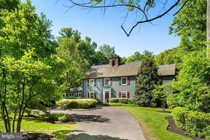 Bucks County meets a touch of New England at this hidden 10.23-acre property, which means a home of superb character and appeal. Set far back off of a quiet country road in an opening of the mature woods that encompasses a large portion of the property’s acreage, this stately colonial measures roughly 5000 square feet, spacious yet warm, with a traditional layout of generously sized rooms and entertainment spaces. Wide oak plank flooring, wood beams and a large woodburning fireplace provide endless amounts of charm and character to the nicely sized kitchen.  A large stone fireplace and a curvilinear wall of windows are focal points in the living room; the windows allow for a huge amount of natural light and views of the stunning property and together they create a room that you will want to spend all your time in. Throughout the home's primary rooms you'll see timeless millwork that adds a special touch whether your style is more modern or traditional. The home has two primary suites – one upstairs and one on the main living floor. The first-floor primary suite is a newer addition to the home and is complete with a large ensuite bathroom with a bonus slipper-back soaking tub, a comfortable bedroom with plenty of light and an enormous space for a walk-in closet. The second-floor bedrooms are generous in size with two of the four bedrooms on this floor serviced by ensuite bathrooms.  Laundry is on the main living floor adjacent to the kitchen and a window- and French door-lined breezeway that could double as a greenhouse in the winter. The main house is complete with an oversized 2-car garage with walk-up storage space above.  Just up the driveway is a recently updated guest cottage with a 1-car garage – ideal for an at-home office or for when you have out-of-town guests.  All this in a highly coveted location with endless privacy, yet moments from Doylestown, New Hope, Carversville, and less than 90 minutes to New York City.