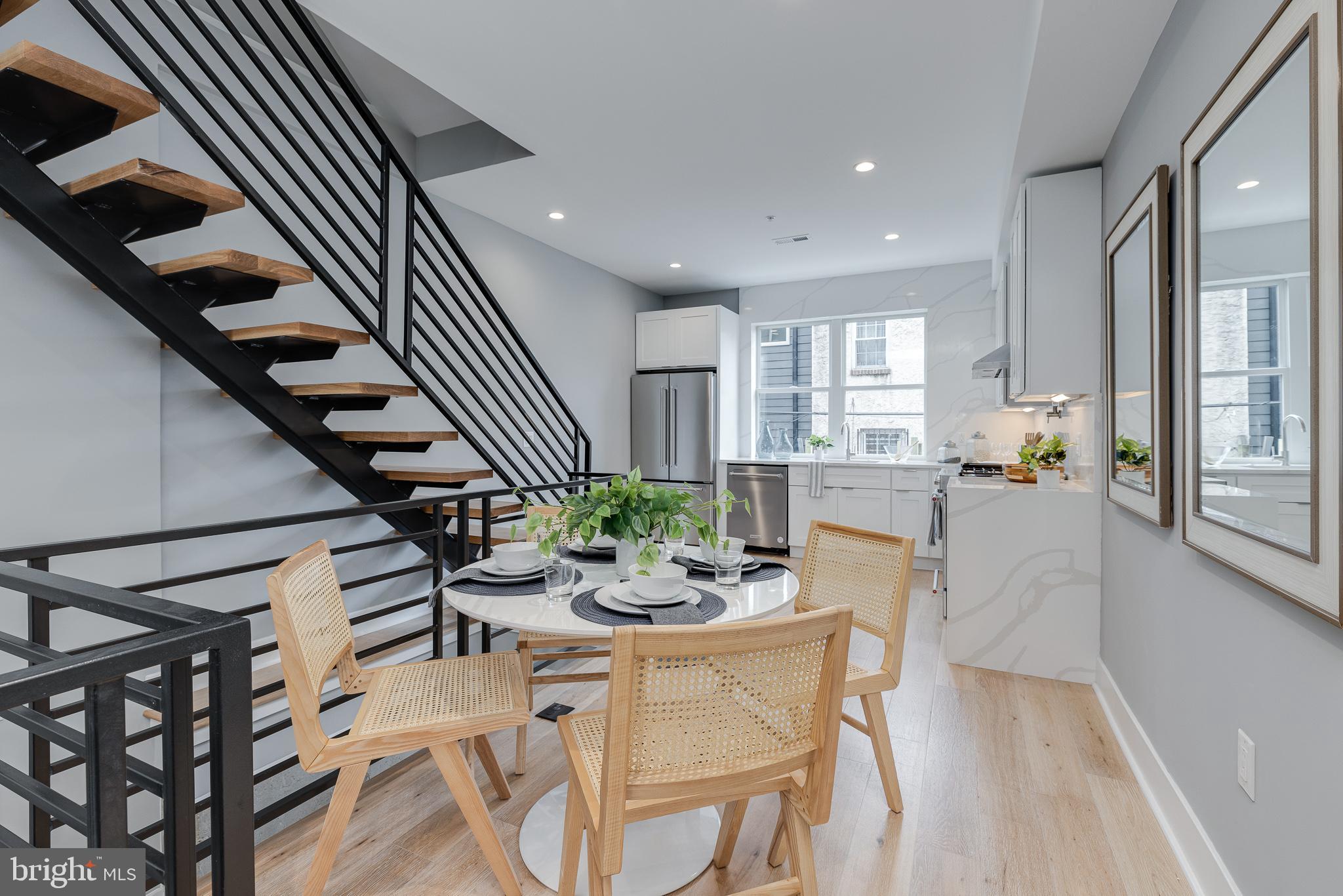 On a quiet block in Graduate Hospital, enter 2227 League Street to be greeted by a sleek modern aesthetic fabricated from the combination of elegant finishes corresponding in warm tones and hues. This 2,000sqft bi-level Philadelphia townhome is a unique build that upon entry alludes to thoughtful design for comfortable living, while remaining a showpiece worthy of entertaining friends and house guests. White oak hardwood plank floors lead into a living space with entries down to the fully finished basement and up to a chef's kitchen. Stone textured wall leads down a few steps to a living area with lots of light from three tiered windows and a full sized egress door. Down a few more steps you’ll find a huge storage and utility room, full bathroom and washer/dryer closet. Practical and thoughtful layout design makes this space conveniently transformable into an ensuite for any guests to visit. Offering privacy with its own access this space ensures guests can enjoy this space undisturbed, without restricting it to a bedroom area only. It can be utilized comfortably for any den purposes the remainder of the time and it can serve both purposes with ease. Notice in the chef’s kitchen that again no details were spared when creating a dream cooking space. Beautiful white tile extends from the counters all the way to the ceiling behind the sink and stove areas, an uncommon feature offering longevity to the cleanliness of your workspace. Vent hood above the range and full sized cabinets flank the stainless steel five burner range, equipped with pot filler. Enjoy views and morning light from the double windows above the sink. Up the open staircase the glass wall offers a clear view of the 2nd floor and boasts some European influence of design flair these builders have developed. Two full sized bedrooms have three windows and full sized closets with built-ins installed. They share a bathroom on this level with textured tile and a stylish green vanity. The entire third floor has a pocket door and is a dedicated primary bedroom suite. The full sized bedroom has more space and extended light. The closest the size of a full nursery is built out to organize and display all of your most cared for possessions. It gets natural light from the bedroom, as well as from the second door leading into a very elegant bathroom. White marble tile from floor to ceiling perfectly complements the small tile used inside the full sized glass shower that includes a giant soaking tub. Double vanities, higher end mirrors and simple fixtures create the most lovely clean environment to prepare for the start and end of your day. A roof deck with panoramic views of the skyline and a wet bar just inside completes the tour of this great home. Quiet luxury and smooth lines really speak to the quality of workmanship and consciousness of style.