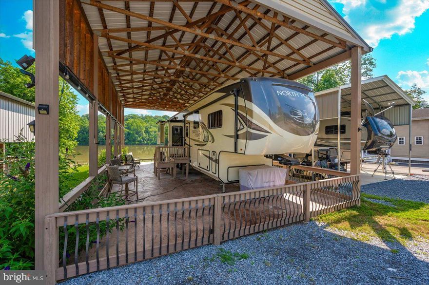 Waterfront in River Bend!!! This is your chance to own a piece of serenity.  Located in gated River Bend seasonal campground (from April 1st til November 1).  100% turn key water-front property with a  2018 Joyco  North Point luxury 5th wheel camper, outside TV,  patio furniture/bar and a blackstone grill that all convey!!!
Beautiful landscaping , partially fenced yard, enormous 24x45 pavilion with sun shades, and a stamped concrete patio.  Fence is removable if needed. This truly is a must see!!!  The 45 ft. Luxury Joyco camper has a  bedroom equipped with a king size bed, lots of closet space, washer/dryer hook up and a TV.  Living area has 3 leather couches, 2 pull out beds , and a large TV that slides into cabinet when needed so you can enjoy the picturesque views of the water.  Kitchen boasts a full size refrigerator , pantry, coffee bar area with lots of storage.  Annual dues are approx. $1900 annually and they include water, trash, electric, and sewer pump out, use of 3 pools, mini golf, basketball courts, tennis and horseshoes . Community also has a camp store, laundry mat, church fellowship , and a nice restaurant/bar. There are several large pavilions which are available for rent for special events as well. Don't let this one pass you by!!!