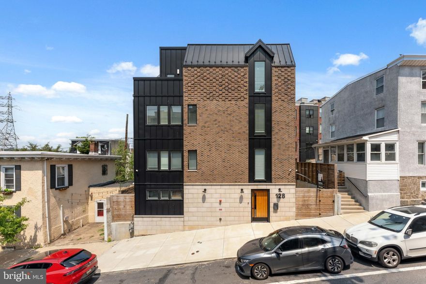 A rare gem in the heart of Manayunk, this detached, custom-built (late 2022) 4-bedroom, 4.5-bath residence offers an unmatched blend of luxury, space, and thoughtful design, just a short stroll to the vibrant shops and dining on Main Street. Spanning over 3,600 square feet, this home breaks the mold of cookie-cutter new construction with steel beam engineering that eliminates interior supports, creating a true open-concept living space on the expansive second floor. The gourmet kitchen is a chef’s dream, featuring a 36" range with pot filler, walk-in hidden pantry, commercial-grade side-by-side fridge and freezer, 10' island, and seamless flow to the dining and living areas—all drenched in natural light. Step out onto the heated balcony overlooking Burnside Street for your morning coffee or evening cocktails. With two primary suites, the main one boasts a private lounge, office nook, dual custom closets, a spa-inspired bath with a floating tub, 60” double vanity, and a large shower with two benches. A 4-stop elevator services all living spaces. The full-perimeter roof deck is ideal for entertaining or unwinding with panoramic views. The two-car garage, additional two-car parking pad, and side yards for pets or storage round out this exceptional offering—urban luxury living with rare privacy and space. Enjoy approximately 8 years remaining on the tax abatement and exceptionally low property taxes, making this a smart investment as well as a stunning home.