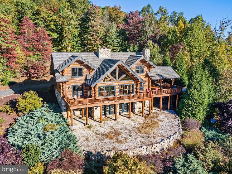 Sometimes dreams do come true. Let quiet country roads take you home to a custom crafted lodge in a superb, elevated site with panoramic 180 degree mountain views. The photos only hint at the amazing engineering of the oversized pine logs throughout this approximately 4,800 sq ft home that is truly an architectural tour de force. The breathtaking great room with its massive stone fireplace (one of three!), gleaming heart of pine floors, and seemingly endless sweeping vistas is truly a wonder as is the amazing, adjoining party deck and dining pavilion. The main and upper floors have three en suite bedroom + a terrific loft study/den. The walkout lower level features a bright rec room, cozy den, full bath, and even an office currently used as a fourth bedroom. With economic geothermal HVAC, this is a home for all seasons. Come and experience the peace and tranquility of this magical home. You may well never want to leave. Truly a Blue Ridge Mountain High!