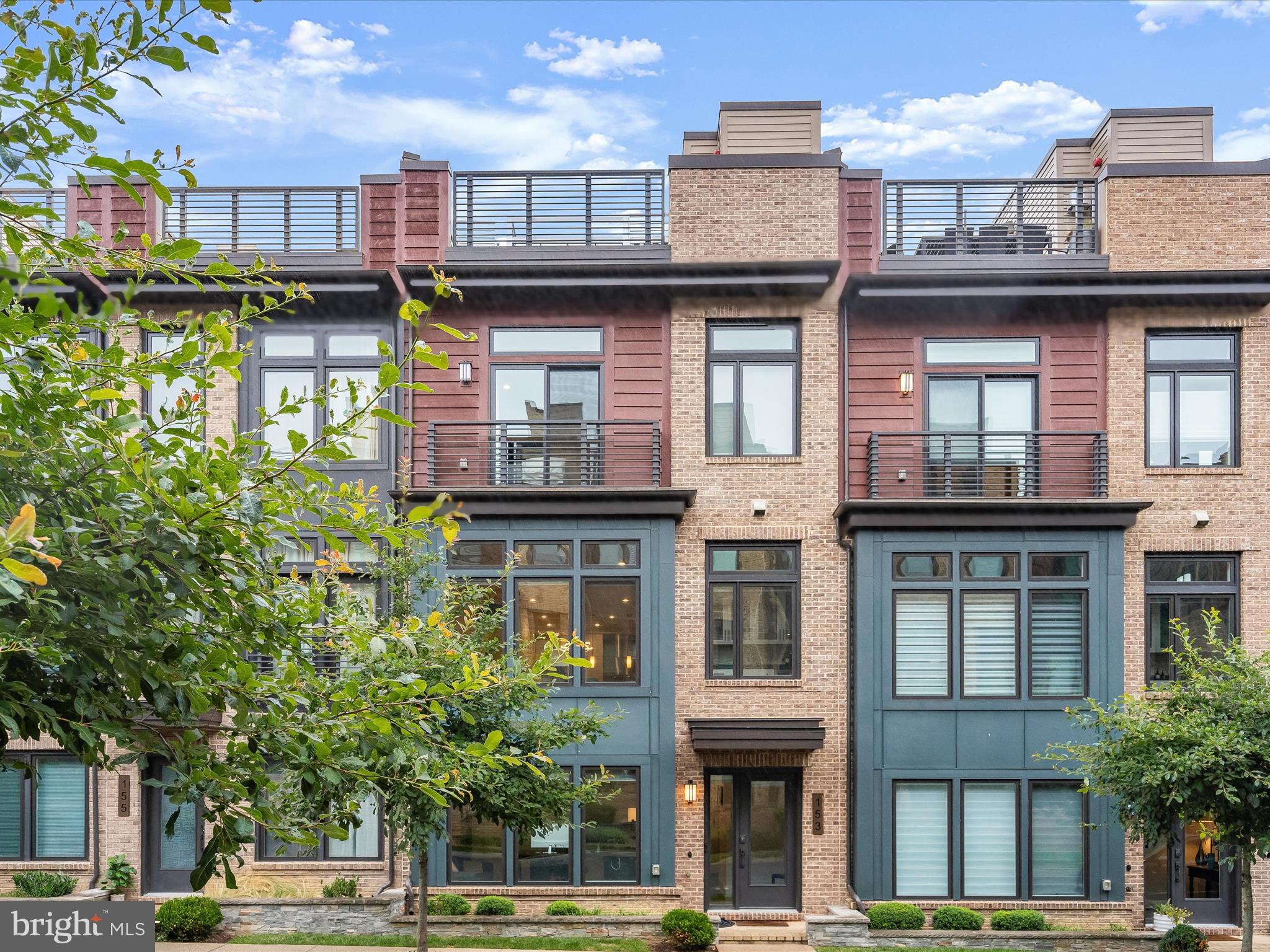 Introducing this exceptional four-level townhome in the sought-after Grosvenor Heights community in Bethesda, offering four bedrooms, three and a half bathrooms, and remarkable details at every turn. Built in 2019 by award-winning builder EYA, this home provides ultimate convenience with an elevator serving each level, including the rooftop terrace. Step inside the foyer where beautiful hardwood floors and a neutral color theme set the tone that continues throughout the home. The entry level includes a bedroom with a private ensuite bathroom featuring a walk-in shower, ideal for guests, those seeking a quiet retreat, or a home office. This level also provides access to the rear two-car garage. Upstairs, the open concept main level boasts tall ceilings and abundant natural light from oversized windows. The gourmet kitchen is a chef’s dream, appointed with high-end appliances including a five-burner gas cooktop, range hood, built-in microwave and wall oven, as well as a hidden refrigerator and dishwasher. Quartz countertops, a tile backsplash, soft-close cabinetry with under-cabinet lighting and pull-out storage, and a center island with seating complete the space. Step onto the balcony off the kitchen for morning coffee or casual dining. The adjoining dining area is ideal for hosting gatherings, while the living room features a cozy gas fireplace and a discreet wet bar for coffee or cocktails. A half bathroom on this level adds convenience. Up one more flight, the bedroom level showcases the primary suite with two walk-in closets and sliding glass doors with custom motorized curtains. The luxurious ensuite bathroom offers a dual-sink vanity and oversized frameless shower with bench seating. Two additional bedrooms, a hall bathroom, and a laundry closet complete this level. The top level is entirely dedicated to the rooftop terrace, designed for both relaxation and entertaining. Highlights include a motorized retractable awning, wet bar tucked behind a garage-style door, gas fireplace, built-in grill, and views of the surroundings. Every detail reflects thoughtful craftsmanship, from custom closet built-ins to modern lighting and finishes throughout. Enjoy this convenient location minutes from the Grosvenor-Strathmore Metro Station, I-495, I-270 and other commuting roadways. Explore the local surroundings, with walking and biking trails, nearby Fleming Park, Wildwood Shopping Center, The Music Center at Strathmore, downtown Bethesda and more. Tucked among lush greenery, this serene setting offers an unparalleled lifestyle close to everything you need.