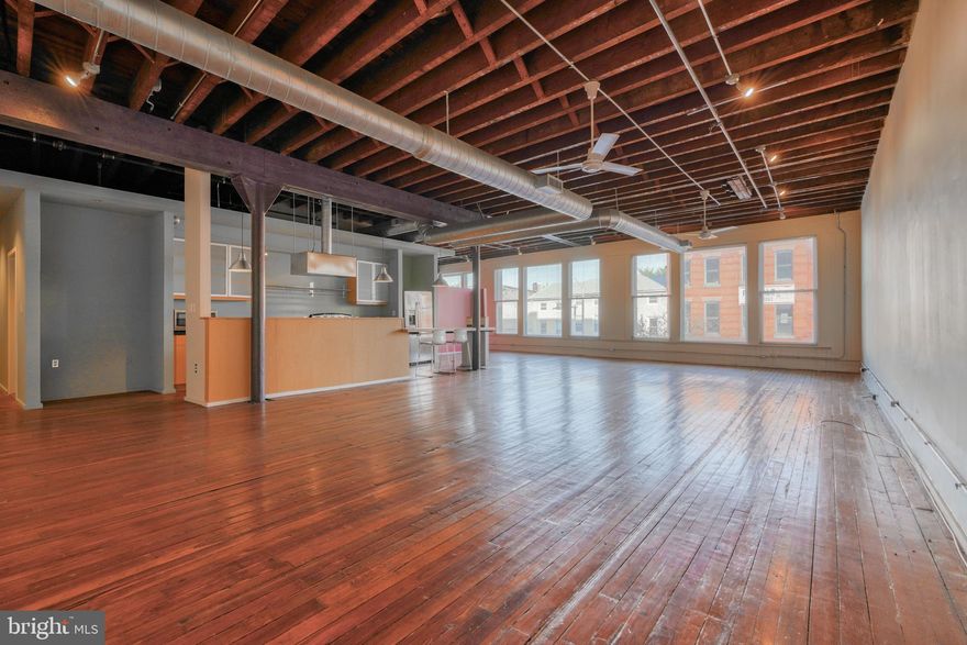 Welcome to The Federal Hill Lofts located at 1000 S. Charles Street--the coolest building. you didn't know existed. Once a former bowling alley, these lofts are tucked away right in the heart of Federal Hill above the CVS on historic South Charles Street. Unit 203 is a gorgeous unit with TONS of natural light, sweeping views of Charles Street through the 7-foot+ windows that run the entire back wall.  The ceilings are over 10 feet tall and have exposed rafters, industrial ductwork, exposed beams and space, space, and space galore. This unit is  over 2000+ square feet of open-concept living. There are no private bedroom walls though there is an  existing partition wall. The space most commonly used as the primary suite has a walk-in closet and direct access to a full bathroom with double vanity. There is a second full bathroom with a double vanity. The kitchen is large with a center island made from the original floors of the old bowling alley. There are industrial lights, tons of cabinets, and lots of counter space. Additionally, there is a separate storage room with a stackable washer and dryer. One space parking space comes with this unit. The parking lot is located behind the building. ***This building is not FHA or VA approved and will not support traditional lending. Buyer either needs to pay cash or use a portfolio lender for a loan.  Regular loan WILL NOT WORK.