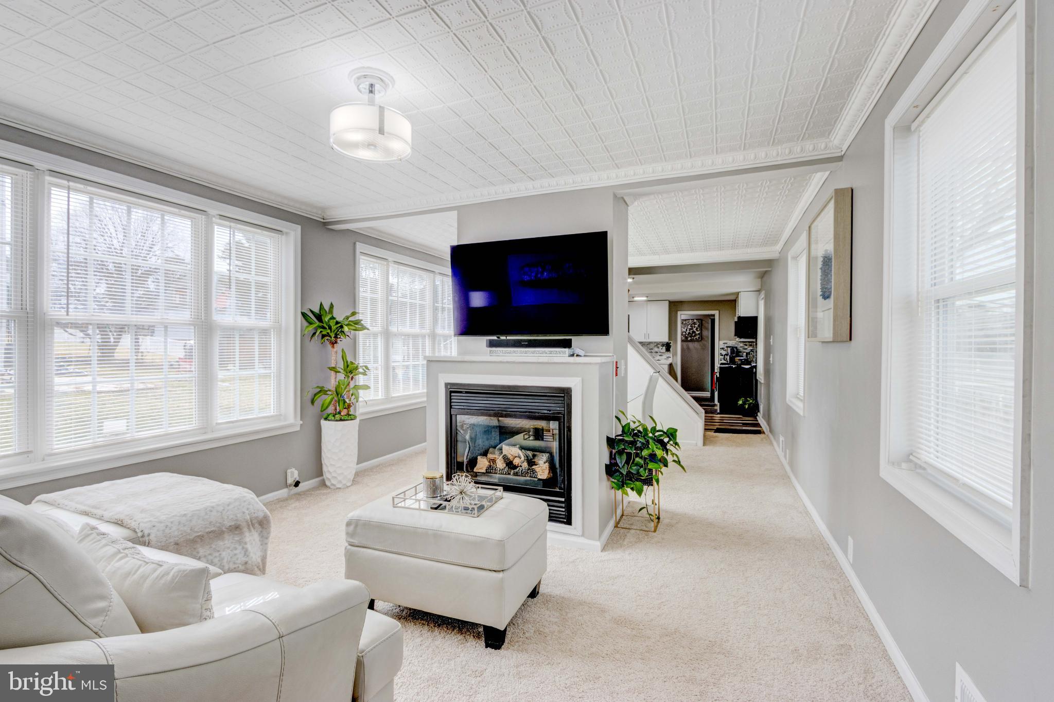 Experience the charm of this beautifully renovated 3-bedroom, 2-bath Colonial home, perfectly situated on a level lot in Halethorpe’s sought-after Joshua community. Flooded with natural light, this home boasts a seamless blend of modern updates and classic character. Step into the sunlit foyer—an ideal space for a home office—before entering the open-concept living and dining areas. Original tin ceilings with decorative crown molding, a cozy gas fireplace with a quartz mantel, and abundant natural light create an inviting ambiance. The updated kitchen features sleek quartz countertops, a stacked stone backsplash, new LVP flooring, stainless steel appliances, and a charming breakfast nook. The main level also includes a laundry room with an adjoining full bath, a storage closet, and direct access to the expansive refinished deck—perfect for outdoor relaxation with scenic tree-lined views. Upstairs, you’ll find three spacious bedrooms, all freshly painted with new carpeting, along with a stylishly updated full bath showcasing honeycomb tile flooring, a new vanity, mirror, and lighting.
The lower level offers walk-up access to the backyard, new windows, a waterproofing system, and fresh paint—ready for your personal touch. Additional features include a repainted sidewalk, a convenient parking pad, and thoughtfully refreshed landscaping. Move-in ready and brimming with character, this home is a must-see!