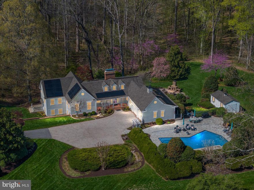 Tucked into nearly nine acres of preserved woodlands and lush, curated gardens, 20 Harwood Drive is a one-of-a-kind retreat where every detail has been thoughtfully designed and beautifully executed. Just minutes from Annapolis, this serene country estate blends natural beauty with top-tier luxury. As you arrive, a private sweeping drive winds through manicured grounds and sets the tone for what’s to come. The paver parking area adds elegance and function, while beautiful gas lanterns frame the front of the home, casting a soft, welcoming glow. Step inside to an extremely inviting foyer, framed with beautiful hardwood flooring and custom moldings that immediately set the tone. Natural light pours through oversized windows and skylights, and the main living space features custom built-ins and a striking brick fireplace with built-in wood storage. From the moment you enter, the home exudes a serene and soulful energy—offering warmth, peace, and a deep sense of connection to nature. This home feels like an escape to the countryside of another life—one where every detail matters and nothing feels rushed. The kitchen is truly the heart of the home, anchored by a massive walnut island and exposed wood beams overhead, with a seamless blend of soapstone and quartz counters, Wolf stainless steel appliances, a warming drawer, Wolf tabletop oven, wine fridge, floating shelves, and a tucked-away coffee nook. A separate scullery provides additional prep and storage space with matching soapstone counters, and just off the scullery is a beautifully appointed full bath with a custom tiled glass shower—ideal for rinsing off after a dip in the pool or time spent exploring the outdoors. The grand primary suite is a private sanctuary of its own, featuring tray ceilings, wooded views, and an enormous walk-in closet with storage for everything. The ensuite primary bath is exquisite, filled with natural light and complete with a deep standalone soaking tub, an amazing custom-tiled walk-in shower, dual vanities,  and a Japanese toilet. All the baths throughout the home are equally stunning, with elevated finishes and thoughtful design.   One of the guest bedrooms also features its own private ensuite bath, offering comfort and privacy for overnight visitors. The laundry room is both functional and stylish, with a deep sink, soapstone folding counter, and large-capacity washer and dryer. Step outside into the kind of outdoor lifestyle most only dream of: the completely redone saltwater pool and surrounding deck area are framed by lush gardens, mature flowering trees, and endless hydrangeas. A sunken stone patio with wood-burning fireplace invites year-round gatherings, while a large deck off the kitchen overlooks the forest and gardens below. Wander down your own private wooded trail to a peaceful creek, or explore the rolling hills of the horse and hiking path that winds through the property. The oversized garage includes a Tesla charger and easily fits two large vehicles. The home is powered by three Tesla Powerwalls, offering 45kw of backup energy with instant power, and a whole-house generator provides added security. Systems and upgrades include new HVAC, new windows and doors, new electric panels, a new well pressure tank, new water softener, and a brand-new septic system. The 1000-gallon propane tank fuels the furnace, range, fireplace, generator, and is ready for an outdoor kitchen or future expansion. LED lighting surrounds the home and highlights the Hardi board siding, architectural roof, and gas lanterns. Thoughtful interior touches include shiplap walls, woven wood blinds, seeded glass accents, and skylights throughout. An artist studio, greenhouse, or workshop with a private entrance is the perfect place to create, build, or escape. This is more than a home—it’s a lifestyle, a sanctuary, and a deeply soulful retreat where luxury meets nature in every possible way.