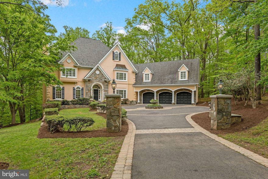 Open Houses Sun., May, 15th 1-3 pm. Tucked away on more than an acre of woodland, 9163 Old Dominion Drive exudes grandeur, appeal and a classical European flair, from its captivating fieldstone and stucco facade to its expansive, lofty interior. Fieldstone walls and woodlands welcome guests to the secluded, winding drive. This masterfully designed home provides ample formal spaces for entertaining and comfortable everyday living, with soaring ceilings and generously sized rooms. The home is easily accessible to the 495 Beltway, as well as to the villages of McLean and Great Falls. 

The stone walk and entryway leads into an impressive two-story foyer with marble floors and exquisite ceiling moulding. Beautiful hardwood stairs wrap around the circular, central foyer, which provides seamless access to the main living areas. Residents and guests are welcomed into a gorgeous two-story family room with floor-to-ceiling windows offering unencumbered, panoramic wooded views. A central wood-burning fireplace with a dramatic two-story fieldstone wall creates a striking focal point and a coffered ceiling adds a refined touch. A sweeping rear deck is accessible from both the family room and the kitchen, perfect for outdoor entertaining. Airy and open, the kitchen features a large island with prep sink, granite counters, a butler’s pantry with a third sink, as well as an additional walk-in pantry. The suite of stainless-steel appliances includes a Viking double-oven professional range, SubZero refrigerator, new Bosch dishwasher and a beverage refrigerator. Detailed moulding continues throughout the formal living room with a wood-burning fireplace and formal dining room with inlay floors and a handsome, ornate chandelier. French doors lead from the foyer into a main-level office with built-ins, hardwood floors and a large storage closet. The adjacent marble-floored powder room is finished with Toto pedestal sink and commode. Sited off the kitchen, a large laundry/mud room provides everyday functionality with new LG washer and dryer, black granite counters, large coat closet and access to the enormous three-car garage. 

Ascend the curved stairwell to the upper-level gallery, where a beautifully designed, opulent primary suite provides the perfect private retreat from daily life. Custom features include two walk-in closets, a spacious marble bath with two vanities, walk-in shower, large soaking tub and water closet. Wainscoting, plantation shutters and exquisite, custom mouldings are found throughout the primary suite. Across the gallery sit three spacious bedrooms with large closets and two full bathrooms. A second set of stairs lead down to the kitchen. A generously sized, full guest suite sits above the garage with a semi-private entrance. Thoughtfully designed, the guest suite features a spacious sitting room with gas fireplace and skylight, a bedroom with en-suite bath and a skylight. Plantation shutters and a cozy window seat create a comfortable suite with extensive privacy for family and guests.

Above ground, the spacious lower level is flooded with natural light with large windows and high ceilings. A generously sized media room, flex space, wet bar, gas-burning fireplace and walkout access to the rear terrace provides the perfect gathering place for indoor and outdoor entertainment. Stairs lead from the terrace to the main level deck creating an easy flow. An additional bedroom and full bath with soaking tub provide comfort for out-of-town guests. At the front of the lower level sits an extensive storage room as well as the utility room with additional storage and a work area.