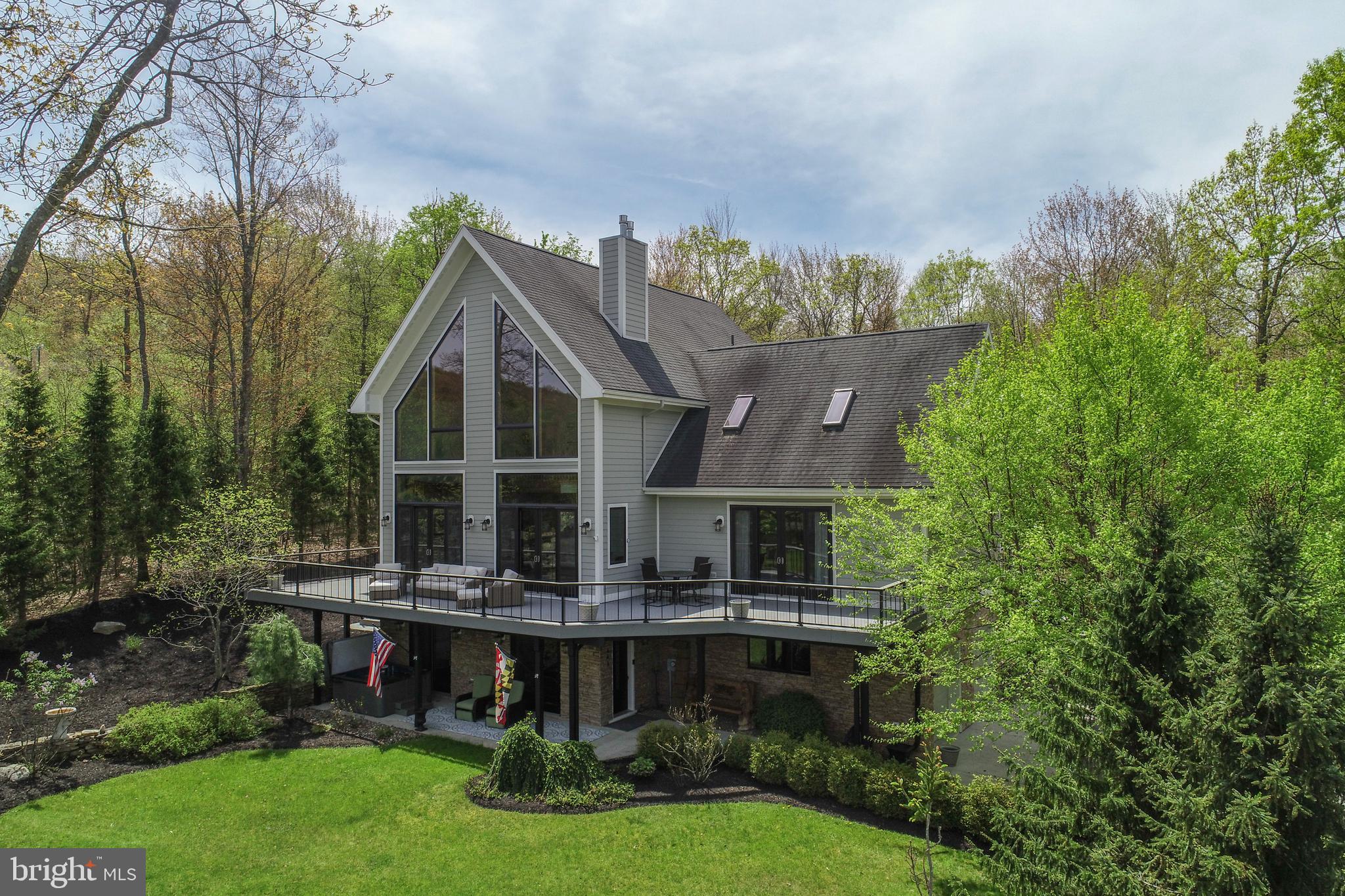 Experience the serenity of Deep Creek Lake from this updated luxury 4 bedroom home with over 5,000+ square feet! The seller’s improvements over the last few years showcase impeccable craftsmanship and outstanding construction quality, both inside and out. Nestled on 2 acres in a private community, enjoy beautiful water views of the lake from the expansive front deck or from many of the interior rooms. The main level provides an open floorplan, seamlessly blending the main spaces for maximum comfort and ease of living. The great room boasts cathedral ceilings, a wall of windows allowing in an abundance of natural light, stunning lake views, stone fireplace, and access to the deck. Spend time in the gourmet kitchen, complete with granite countertops and stainless steel appliances, or venture onto the back deck for outdoor dining and cooking. All four bedrooms are oversized and offer an abundance of space for beds, sitting/lounging, and a dedicated full bath for each - three of which offer private en-suite bathrooms. Relax on the lower level in front of the fireplace or step out to the hot tub waiting on the patio with under deck drainage panels to block the rain. The attached 2-car garage provides ample room for vehicles and all storage needs. Other premium upgrades include tankless hot water, a whole house Aquasana water filtration system, upgraded gas fireplace inserts, and trek decking/railing that is only 4 years old! Professionally landscaped and meticulously maintained, the secluded yard offers a backyard oasis, complete with a spacious fire-pit area with lots of seating. A rare opportunity for an updated home with lake views too in the heart of Deep Creek Lake!