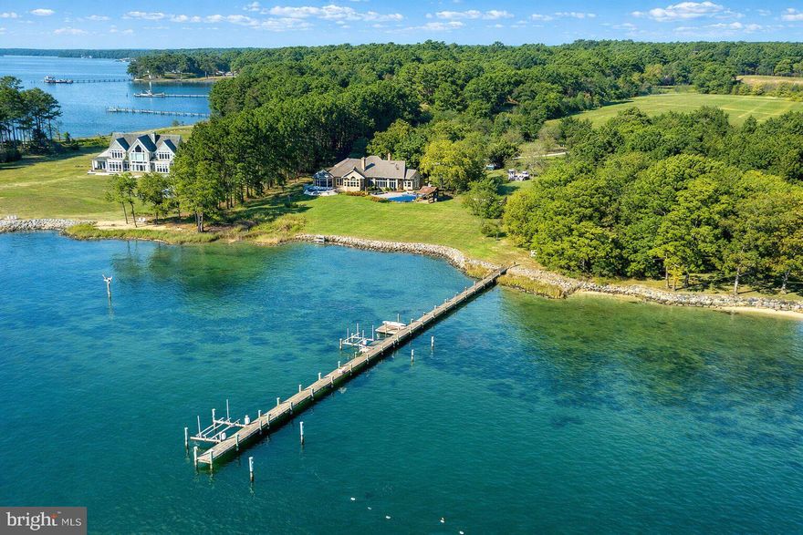 Located within 2 miles of historic St. Michaels this exceptional waterfront estate blends timeless elegance with a resort-style setting. This 4,200± sq. ft. custom, single-level all brick residence showcases soaring ceilings, an abundance of natural light, and panoramic views of Broad Creek from almost every room.  A huge great room featuring a large brick fireplace and open living / dining options. There is a gorgeous gourmet kitchen complete with quartz counters, stainless steel appliances and walk in pantry, seamlessly flowing into a spacious family room with a timeless double sided brick fireplace and built-in bookcase.  An architecturally stunning screened octagonal porch—perfect for relaxing or entertaining. A brick-floored sunroom with gas fireplace and pool bath leads to an expansive patio overlooking the waterside pool, framed by a rock waterfall, and custom gazebo. The luxurious primary suite features cathedral ceilings, French doors leading to the sunroom and a spa-inspired bath with walk in tile shower and soaking tub. Two additional en-suite bedrooms, a large den with custom built-ins perfect for library or additional bedroom, and a spacious butler’s pantry with granite counters, extra refrigerator, stainless sink and additional cabinetry. A separate study and conditioned workshop offer versatile space. Set on five beautifully landscaped acres with southern exposure, the property boasts 370+/- feet of protected shoreline and a 350-foot private pier with 6 feet of deep water. Boating enthusiasts will appreciate the 15,000-lb and 8,000-lb lifts, two additional slips, and a floating dock.  A gated 30' x 40' flower/vegetable garden with raised beds, an oversized 2-car garage and large garden shed complete this beautiful home. Septic is for 3 BR but office could be BR #4.