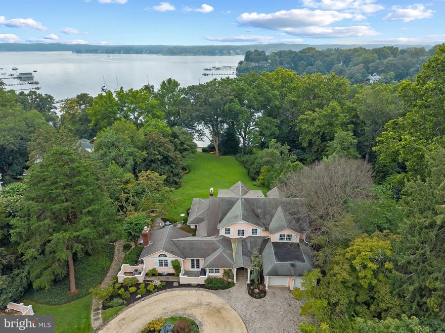 Located in the heart of Olde Severna Park, this water view home enjoys a prime location just steps from one of the area’s top private schools, local restaurants, shops, and the Baltimore–Annapolis Trail. The main level is designed for both everyday living and entertaining, with a formal living room that spans the back of the house and showcases views of Sullivan’s Cove. A sun-filled dining area, office/sunroom, and family room with fireplace and walls of windows create a warm and inviting flow, all with direct access to the stone patio featuring a tranquil water element. The gourmet kitchen with center island opens seamlessly to the family room for easy entertaining both inside and out. Enjoy the spacious waterside recreation room with an adjoining bonus room/potential bedroom, creating flexibility and convenience for multi-generation living.  Spacious laundry, mudroom with second refrigerator, and two-car garage complete the main level. Upstairs, the private primary suite offers a serene retreat with its own balcony overlooking the lush yard and water, a large custom walk-in closet, and a spa-inspired bath. Two additional bedrooms feature ensuite baths, while two more share a generous hall bath. The unfinished lower level adds excellent storage space with an extra laundry area and half bath. The stunning grounds offer multiple exterior entertaining areas including stone patio with water feature and waterfront stone patio for relaxing and watching the serene activity on Sullivans Cove. The detached 2 car garage and circular driveway add to the grandeur and functionality of the property. Olde Severna Park’s voluntary HOA provides access to a sandy beach, swimming area, community pier, and boat launch for kayaks and paddleboards, with boat slips available when available and the ability to moor a boat in Sullivan’s Cove. This home combines water-privileged living, an enviable location, and timeless appeal. Welcome Home!