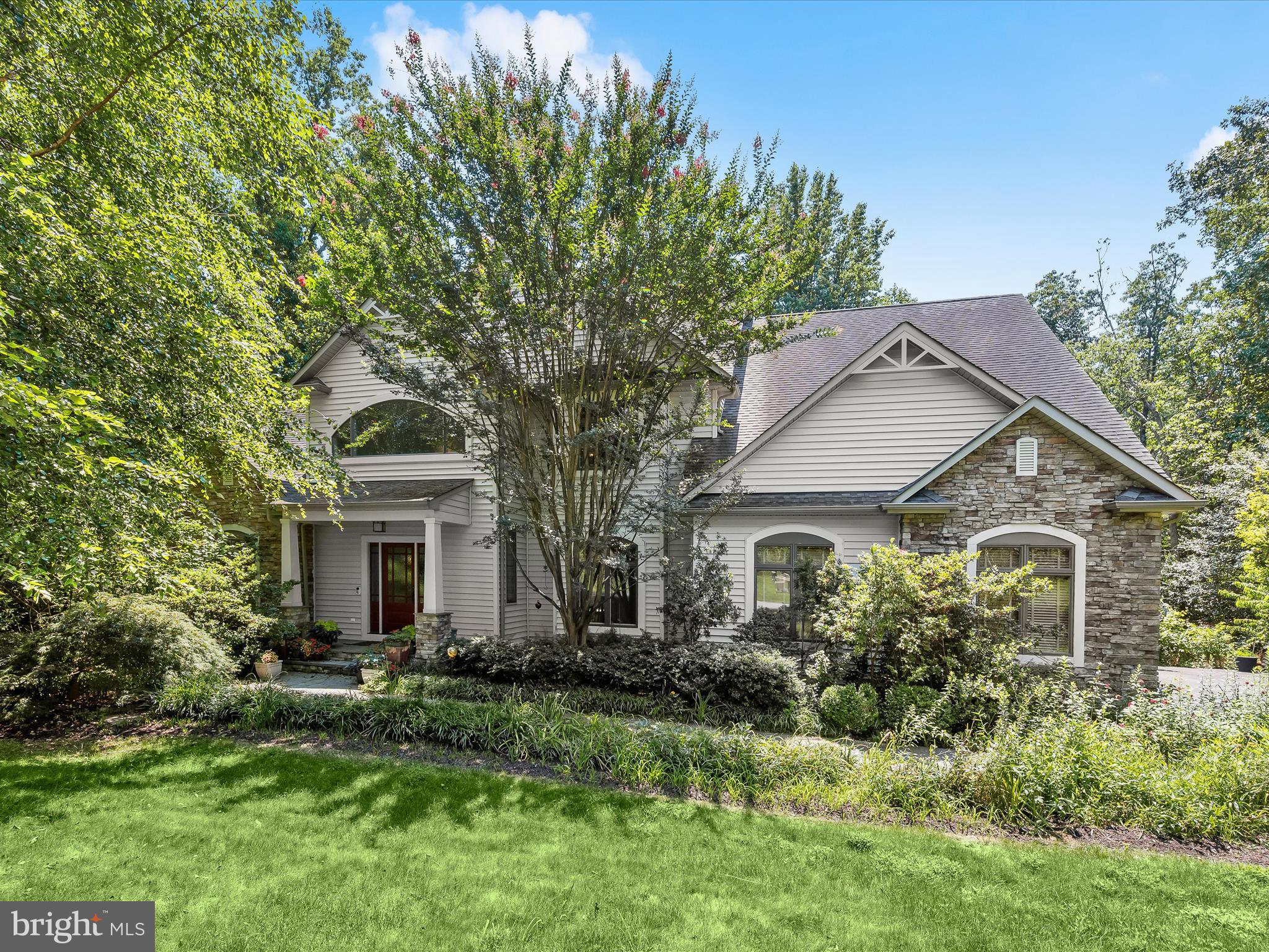 This custom-built contemporary luxury home is thoughtfully maintained and designed by its original owners, blending clean architectural lines with natural surroundings and carefully selected finishes. Offering nearly 6,000 square feet, the residence features 6 bedrooms and 5.5 baths, with spacious interiors, multiple home office options, and flexible spaces that cater to modern living, multi-generational needs, and effortless entertaining. It sits on nearly an acre of landscaped grounds that perfectly complement the home’s sophisticated style. A slate stone walkway bordered by perennial landscaping leads to a solid Douglas fir front door, setting the tone for the refined warmth found within. Inside, the two-story foyer welcomes with stone tile flooring, an antique light fixture, and a chandelier lift, just the first glimpse of the meticulous attention to detail throughout. Beyond the entry, open-concept living spaces unfold seamlessly, beginning with a chef’s kitchen adorned with granite countertops, an island with breakfast bar, stainless steel appliances including wall ovens, and an induction cooktop with range hood, a Reverse Osmosis water system, and not one but two pantries for ultimate convenience. The kitchen overlooks the family room, a comfortable and inviting space centered around a cozy fireplace. Just beyond, the dining room features a wall of lofty windows and a door leading to the deck, while the living room impresses with its vaulted ceiling, skylights, and an atrium door flanked by glass side panels. Here, expansive windows offer peaceful views of the lush greenery that surrounds the property. Step outside to the spacious deck, which includes a screened-in section perfect for relaxing or entertaining, allowing you to enjoy the outdoors without interruption from the elements. Down the hall, a built-in drop zone, half bath, and a spacious laundry room with ample cabinetry offer daily ease. Two main-level office spaces, each with built-in desks, provide private, productive zones for work or study. The main-level primary suite feels like a private retreat, introduced by a sitting room with French doors, and featuring a serene bedroom with fireplace, walk-in closet, and a spa-inspired bath with heated soaking tub, tiled shower, and dual-sink vanity. Upstairs, a loft with a built-in workstation connects to three bedrooms, each with walk-in closets, window seats, and direct access to bathrooms. One has a private en suite, while the other two share a bathroom with their own private sink and vanity areas. A spiral staircase leads to the top-level bonus room with skylights and its own full bath, perfect as a creative studio, guest hideaway, or playroom. Additionally, the room over the garage can be finished and is accessible from one of the upper-level bedrooms. The recently finished lower level is well designed, adding impressive versatility with two additional bedrooms, a sleek full bath featuring a floating vanity and tiled shower, an exercise room, and living and dining areas. The second kitchen is appointed with soft-close cabinetry, a glass tile backsplash, and stainless steel appliances. With a private entrance, its own laundry room, and stylish design, this level serves perfectly as an in-law or guest suite. Additional highlights include a 3-car side-loading garage with Level 2 EV charger, abundant built-in storage throughout, a whole-house dehumidifier, super-efficient geothermal HVAC, and a Solar PV system with battery backup that supports key critical loads such as lighting, refrigeration, water heating and well pump during power outages. The home backs to trees, offering quiet privacy, and is located just 15 minutes from the airport, making commuting easy without sacrificing tranquility. Every element of this exceptional home- from its flexible layout and custom finishes to the serene, tree-lined setting and thoughtfully integrated systems- reflects a perfect balance of luxury, comfort, and livability.