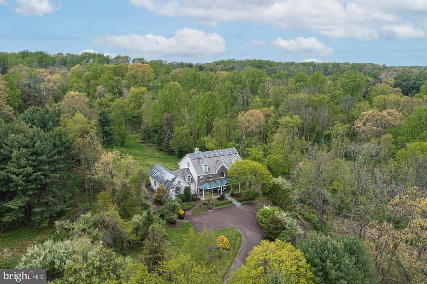 Serene tranquility awaits you in this stunning porch front home nestled in the heart of scenic Solebury Township on over 2 plush acres surrounded by woodlands and greenery. Travel down the winding drive dotted by mature trees and lush landscaping and take note as this breathtaking sanctuary appears out of the woods before you in this enchanting backdrop. Its architectural charm will capture your eye instantly and lure you in to discover what the rest of this alluring haven has to offer. Enter through the grand arched transom entry door which sets the mood as you walk through this thoughtfully planned 5 bedroom home with hardwood floors, stunning millwork, attractive moldings, 11’ ceilings, and 3 floors of wonderful living.  This spacious and light-filled home features a timeless and enduring floorplan, designed for easy living and elegant entertaining beginning with the wood spiral turned staircase which brings a classic grace and style into the open entry as it winds its way to the upper level.  Anchoring the foyer, both the formal living and dining rooms mirror each other with crown accented tray ceilings and custom wainscotting. Take in beautiful views of nature thru an abundance of well positioned wall of windows which seamlessly transports the outside in of the home’s warm and inviting centerpiece, 2-story Gathering Room decorated with floor-to-ceiling, double-sided stone fireplace and open to the neighboring Kitchen. The Kitchen would be any cook’s delight outfitted with soapstone countertops, custom cherry cabinetry, Viking cooking appliances, SubZero refrigerator, eat-at island highlighting a 6-burner gas cooktop, 2 dishwashers, multiple sinks, and sun-filled breakfast area with built-in breakfast bar featuring fantastic storage, beverage fridge and prep sink. The kitchen flows easily on both sides with a Butler’s pantry on one end and a Mud Room boasting radiant floors and housing a pet bathing station, storage and convenient half bath on the other end. A spacious Study with built-ins and stone fireplace is a perfect spot to work from home with access to the bluestone covered terrace thru a set of transom accented French doors offering a place for outdoor entertaining and relaxation with amazing views from every angle. A neighboring, convenient second Study/bonus room leads to a screened-in outdoor patio area. Wake up and watch the sunrise through the set of triple windows of the private level Suite with vaulted beam ceiling, a private bath adorned with a jetted tub and walk-in shower. Head up the craftsman styled rear staircase to a roomy loft space and hallway on the upper level for access to the sleeping quarters housing a Princess suite with full bath and 2 additional bedrooms sharing a Jack & Jill bath. The third level is currently being utilized as an au pair suite featuring a full bath and 2 large walk-in closets with custom organizers but offers wonderful versatility. The lower level is partially finished with a gym/exercise space for the workout enthusiast. Surrounded by 11 acres of protected common area that allow you to relax, rejuvenate and entertain guests while offering beautiful views of nature with wooded privacy plus provide access to a nearby pond lending to such activities as canoeing, ice skating and fishing. Additional home amenities include a 3-car attached garage, central vac system, multi-zone heating/air, electric car charging stations, workshop, solar panels with battery back-up, electric pet fence and a newer cedar roof.  This private sanctuary is truly extraordinary where each season is appreciated and a place where you feel as though you can get away from it all yet close by to main thoroughfares for NYC , Princeton and Philadelphia travelers. Found in one of the most beautiful sought-after parts of Bucks County in the highly regarded New Hope Solebury School District, this location offers great shopping and restaurants along with a breathtaking country feel.
