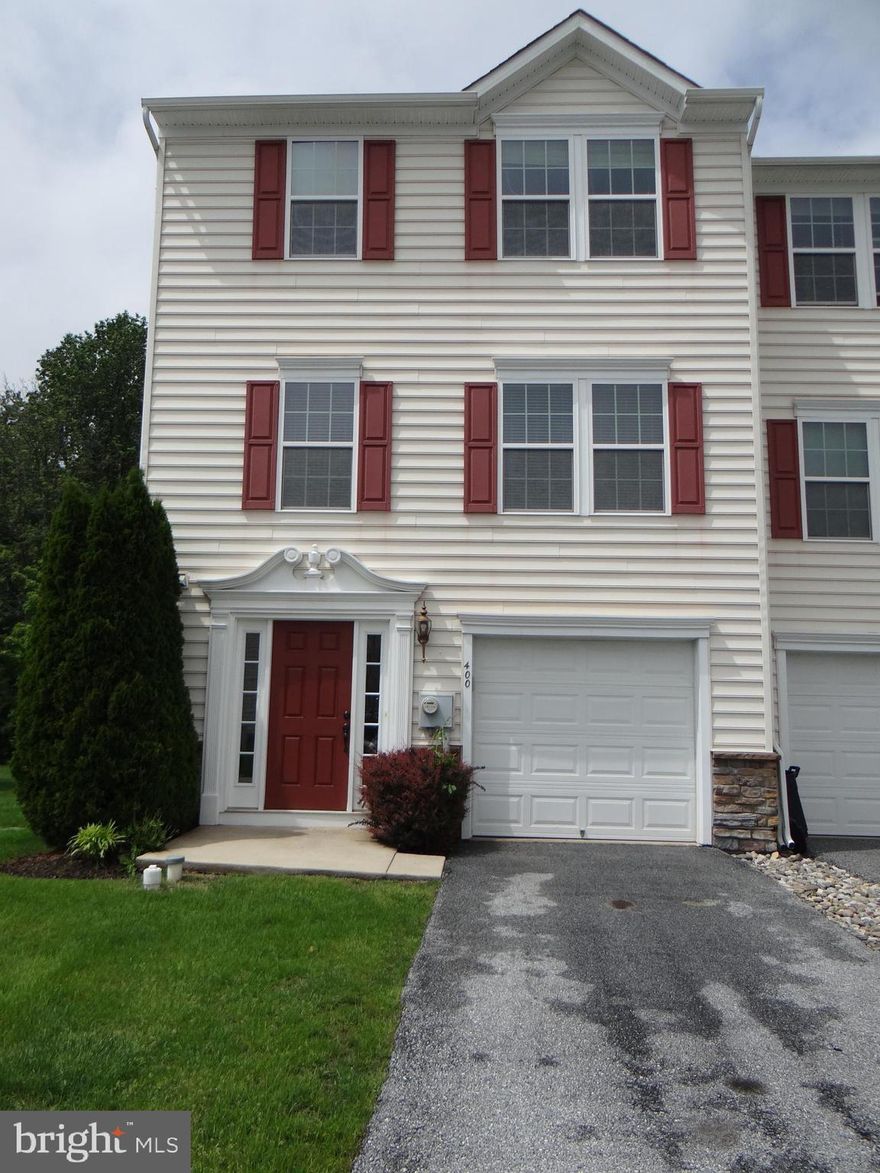 Beautifully maintained and loaded with upgrades, this end-unit townhome offers both comfort and convenience. Nestled at the rear of the community, the home boasts a peaceful, tree-lined backyard. Step into the welcoming tiled foyer, complete with a coat closet, a convenient powder room, access to the garage, and a partially finished flex space—perfect for customizing to suit your lifestyle. This level also features a laundry area with direct access to the backyard.  Upstairs on the main floor, you'll find a bright and spacious living room with a mounted TV bracket and large windows that flood the space with natural light. The adjoining gourmet eat-in kitchen includes granite countertops, a tile backsplash, a center island, and hardwood floors. Just off the kitchen is a versatile bonus room that can be used as a family room, dining area, or sitting room. This space also features hardwood floors, a lighted ceiling fan, and sliding doors leading to the deck—ideal for entertaining or relaxing.  The third floor is home to a generous primary bedroom with a lighted ceiling fan, dual walk-in closets, a TV wall mount, and an en-suite bath featuring a jetted soaking tub, dual vanity, and ceramic tile shower. Two additional bedrooms with lighted ceiling fans and a full hall bathroom complete this level.  The community offers overflow parking, two playgrounds, and a walking trail, and it's conveniently located just minutes from the Route 30 Bypass. HOA services include lawn care, snow removal in common areas, exterior maintenance, and upkeep of shared spaces. Tenants are responsible for utilities and must provide renters insurance before occupying.